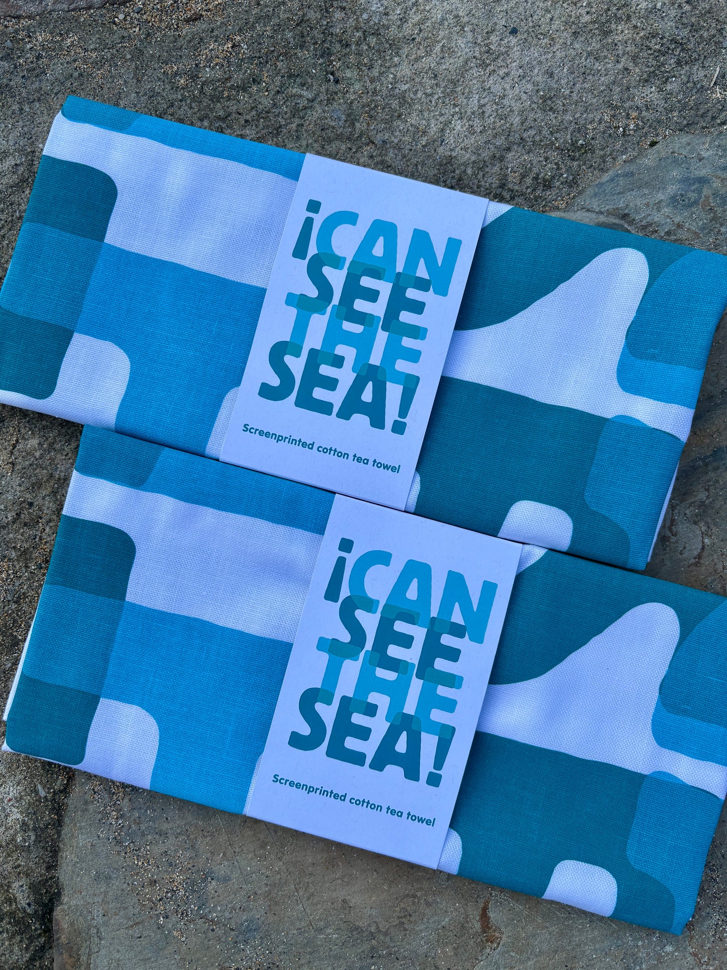 screenprinted cotton tea towel with a "I Can See The Sea!" message and a modern abstract teal/blue block print design nautical kitchen gift for coastal homes
