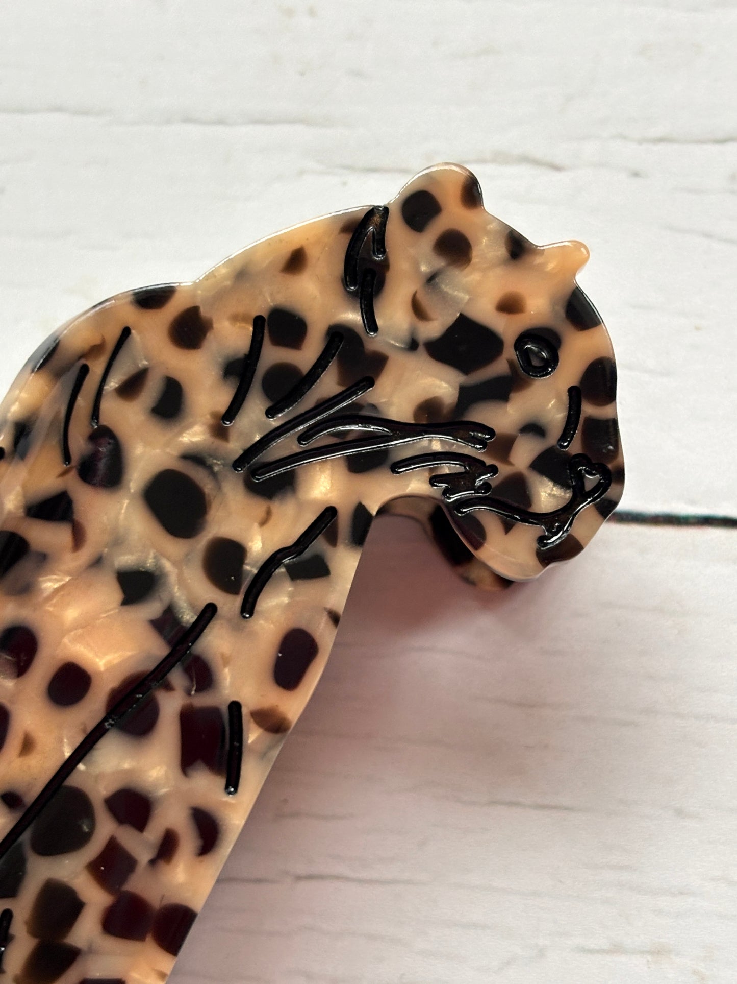 closeup shot of leopard hair claw—glossy beige clip with bold spots, feline silhouette, and secure grip for wild styling