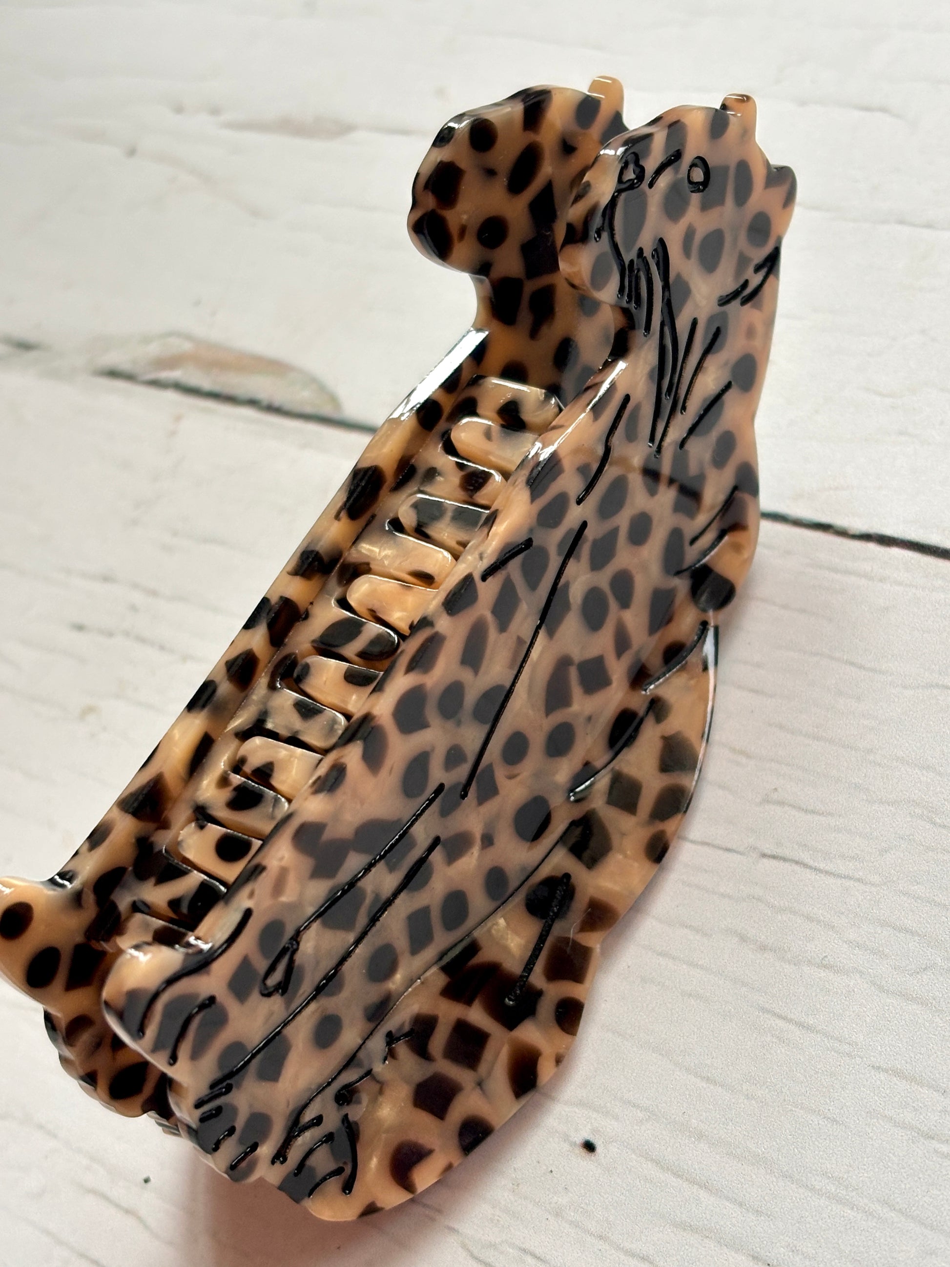 closeup shot of leopard-print hair claw—twin feline design, bold spots, and glossy finish for fierce, statement styling
