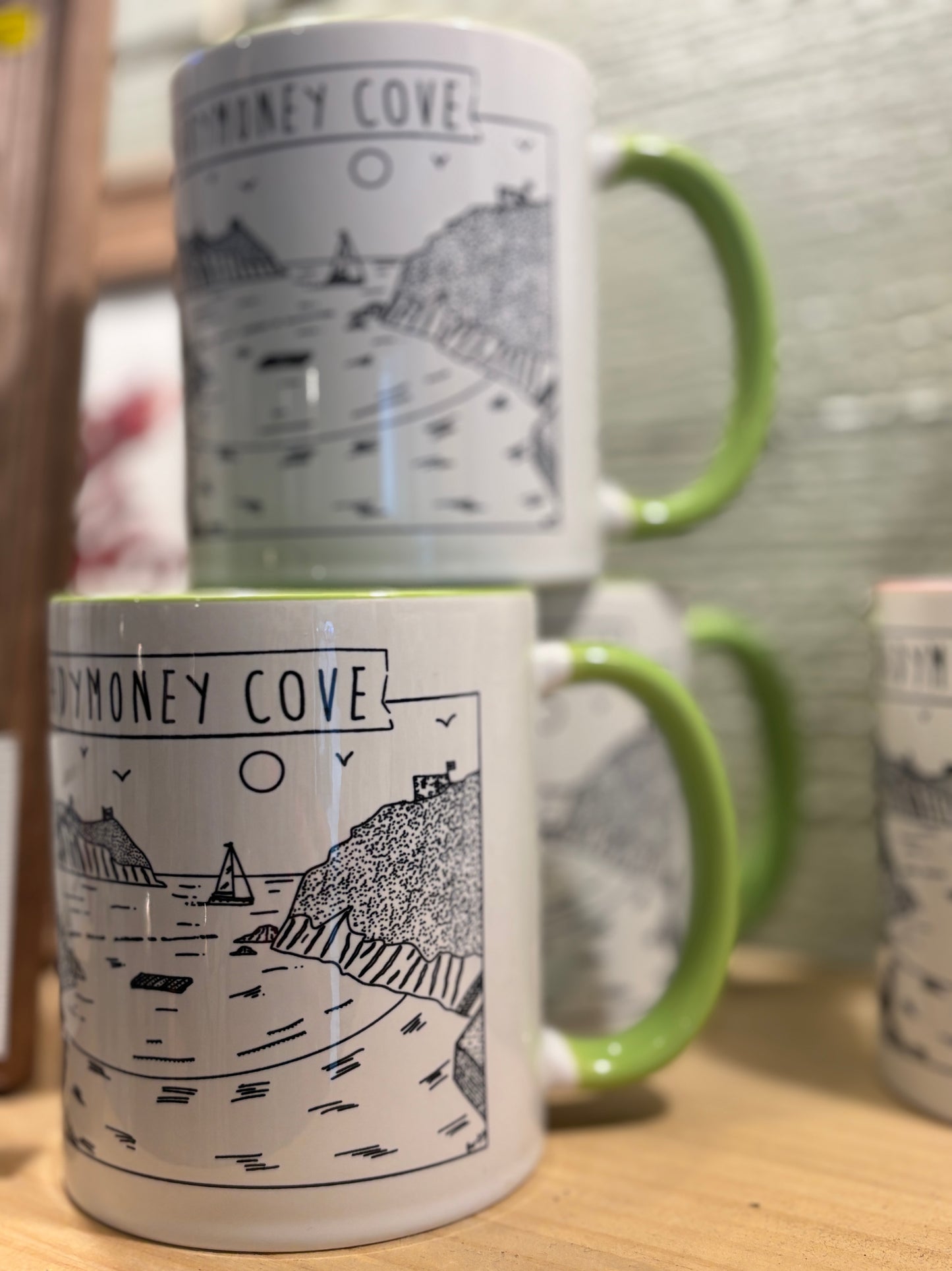 a mug with a lime green handle and interior featuring a black & white illustration of readymoney cove