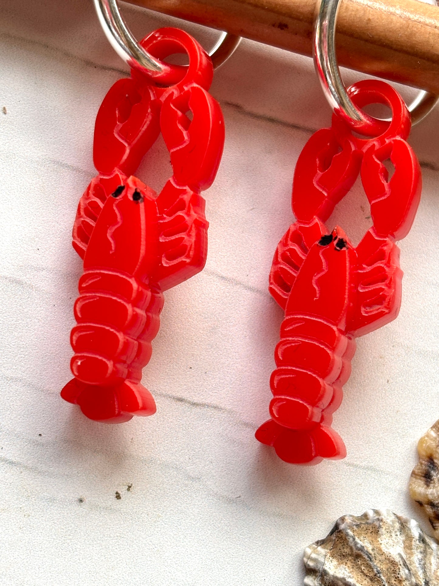 closeup shot of lobster earrings—bright red crustacean charms on silver hoops, ideal for coastal fashion, beachwear, and ocean-inspired gifting