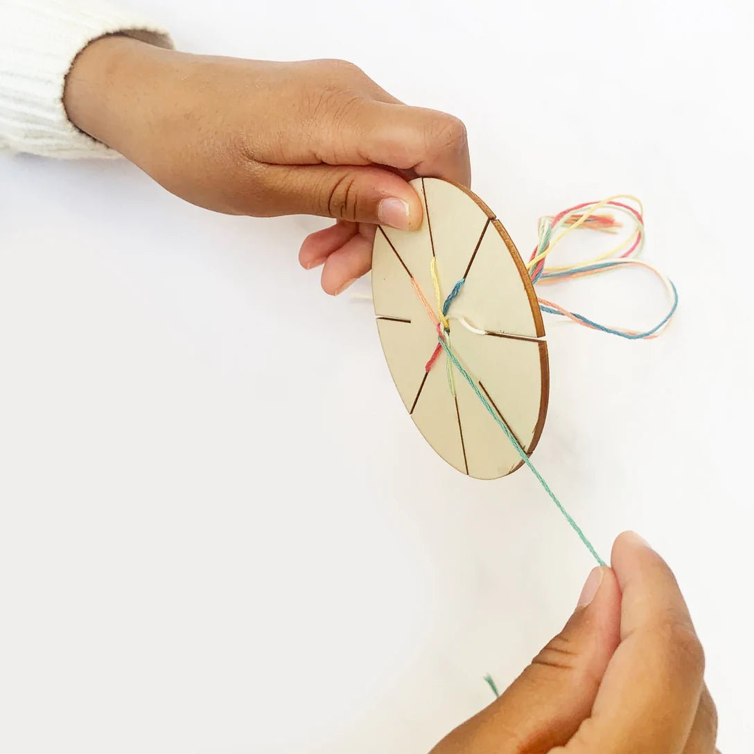 kids weaving a DIY friendship bracelet using the kumihimo loom and colorful thread hands-on craft activity for children