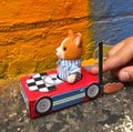 closeup shot of the finished DIY matchbox racing car red car with checkerboard decal & flame, driven by a toy animal model kit for kids