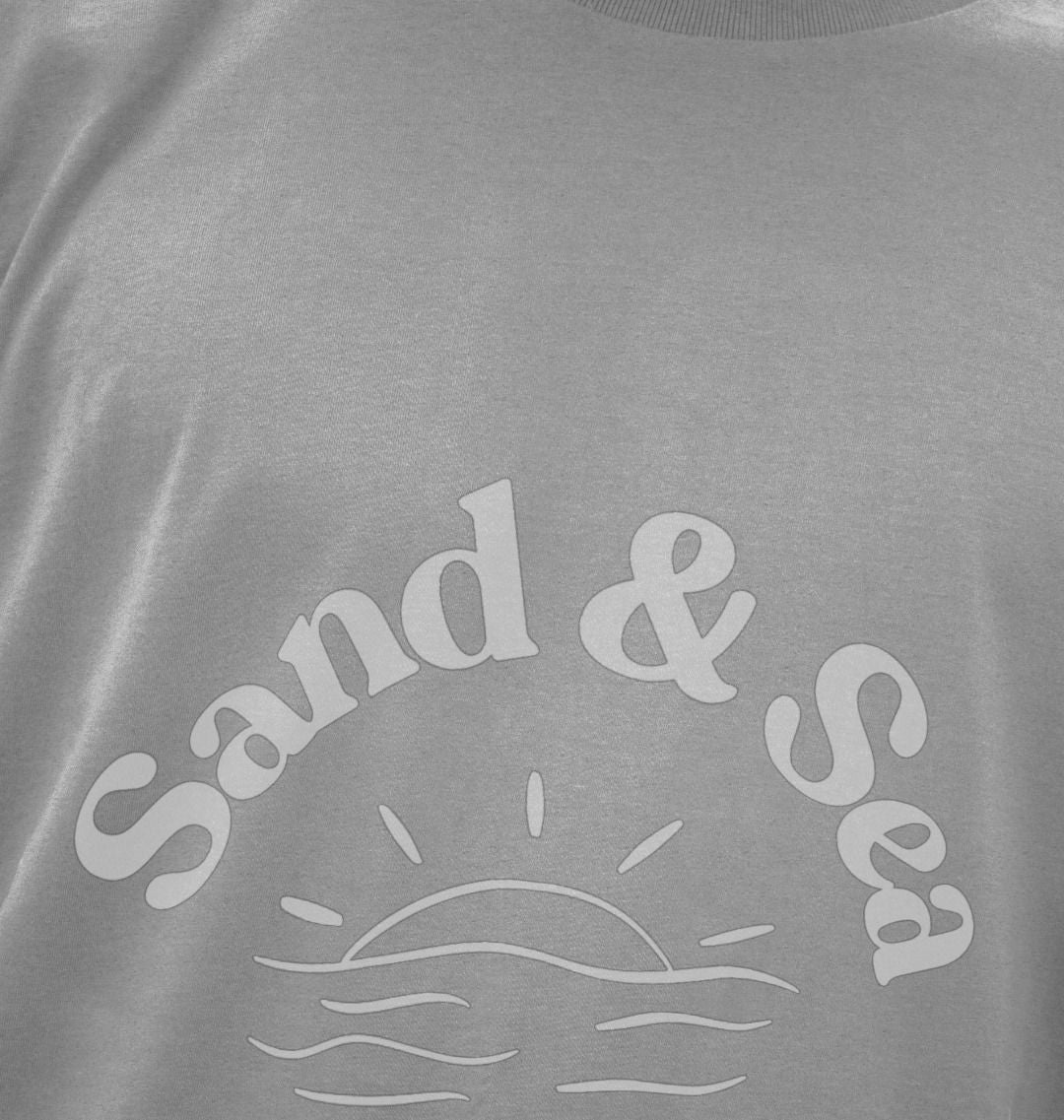 closeup shot of athletic grey T-shirt with white "Sand & Sea" graphic features sun and wave detail men's casual coastal apparel and eco-friendly tee