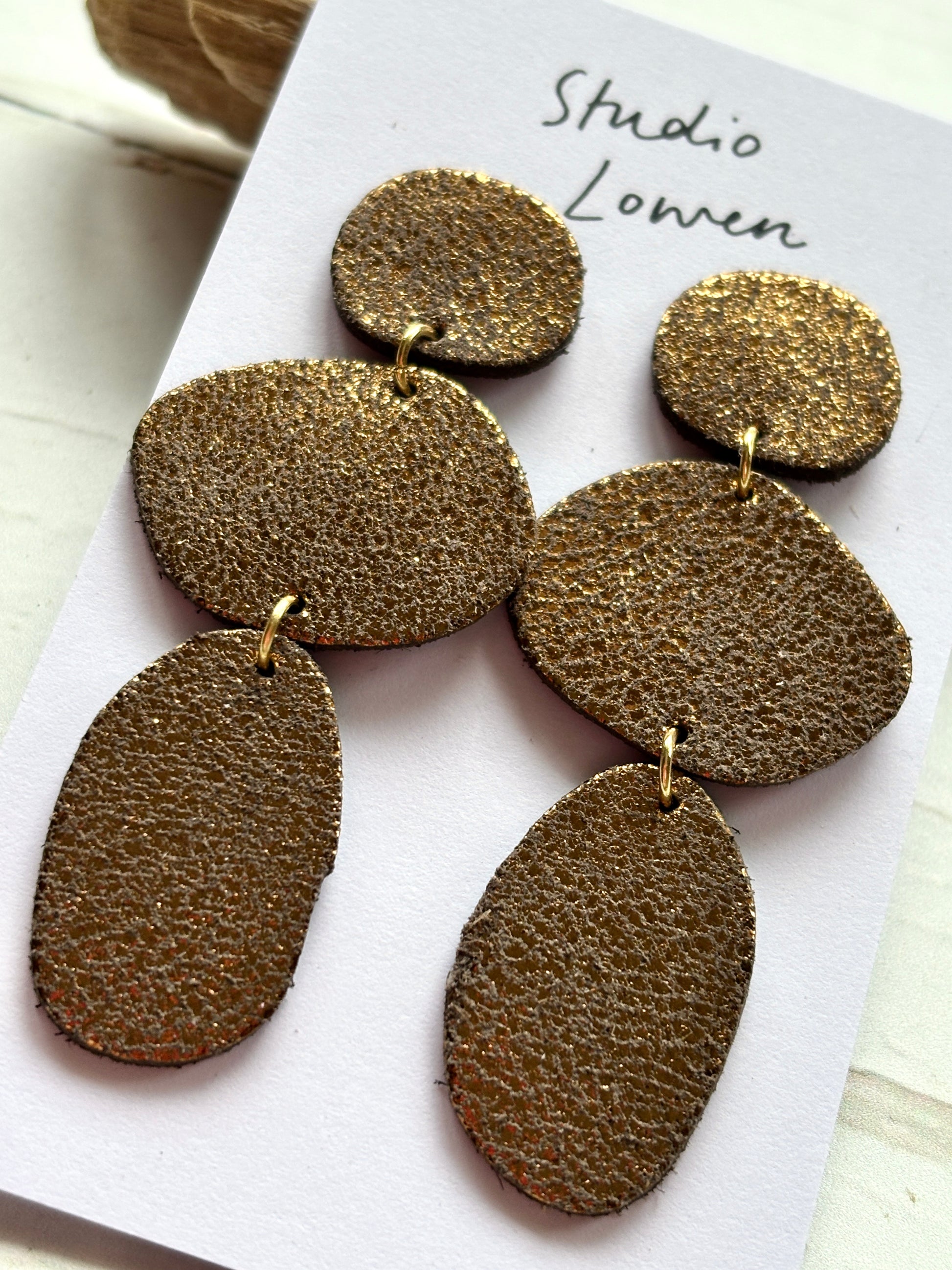 closeup shot of triple bronze leatherette dangle earrings textured multi-oval statement jewelry fall/winter fashion