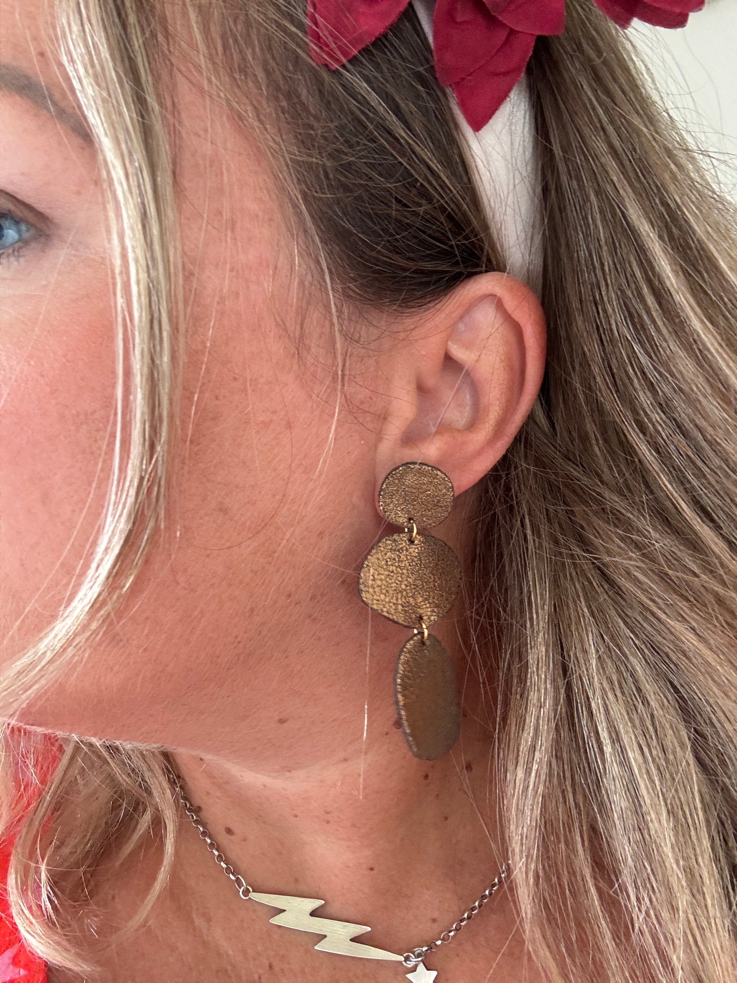 woman wearing triple drop bronze metallic textured earrings long layered leatherette statement jewelry