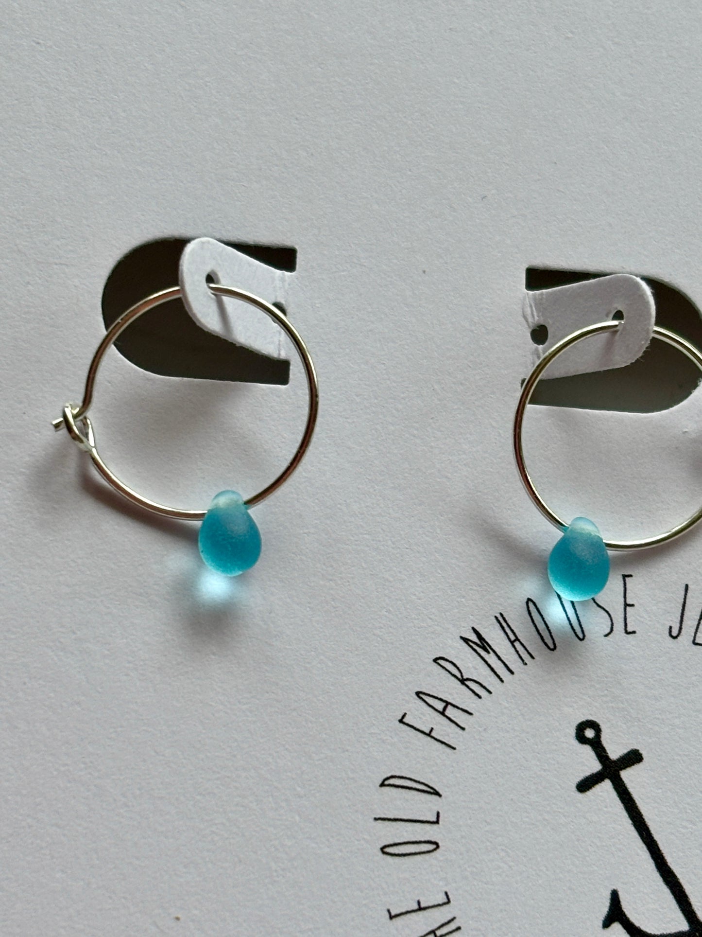 closeup shot of bright blue glass teardrop hoop earrings, minimalist sterling silver beach jewelry, coastal everyday gift for her