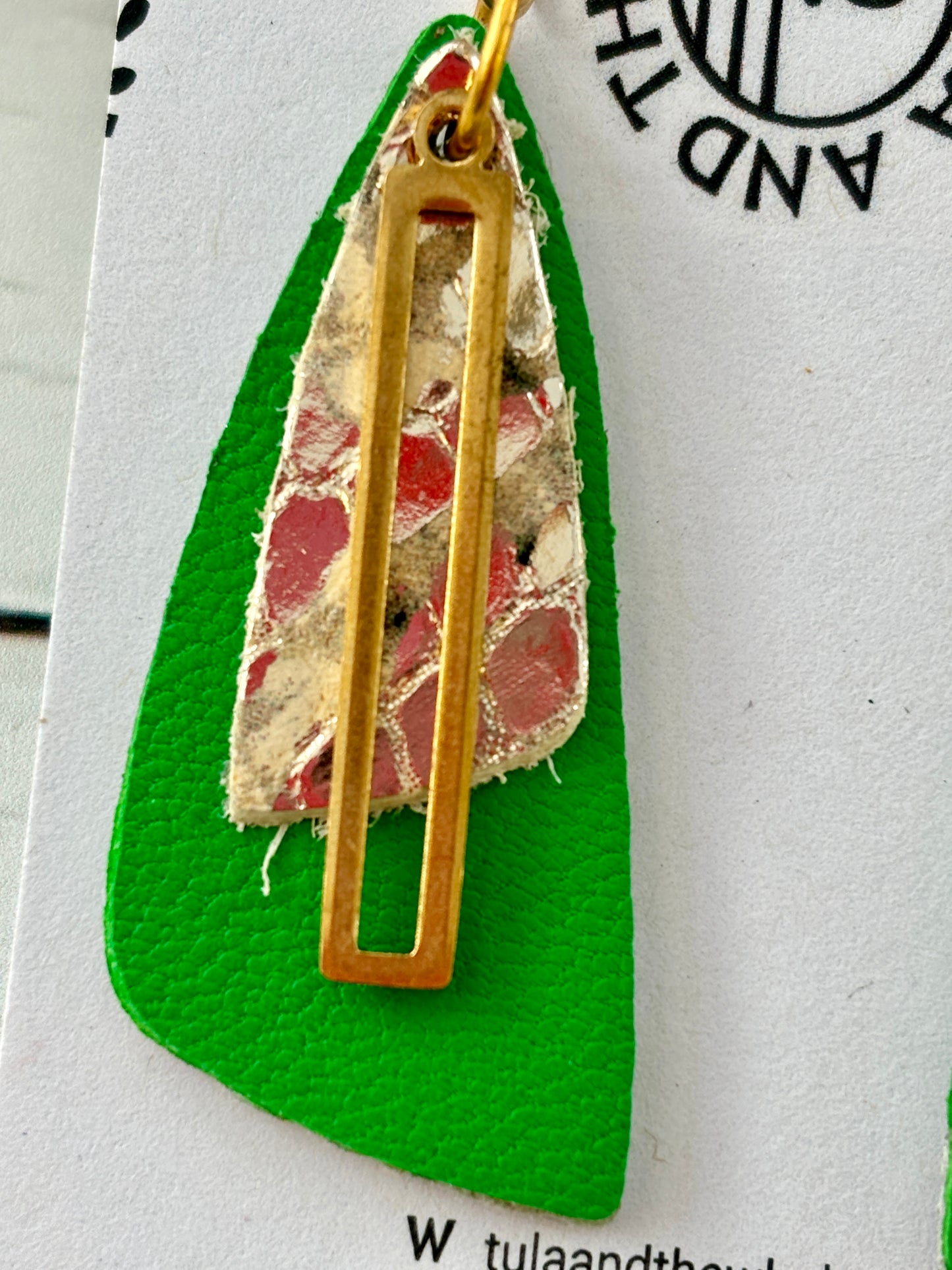 closeup shot of handmade green leather earrings with gold snake-textured layer and cut-out accent—bold statement jewelry