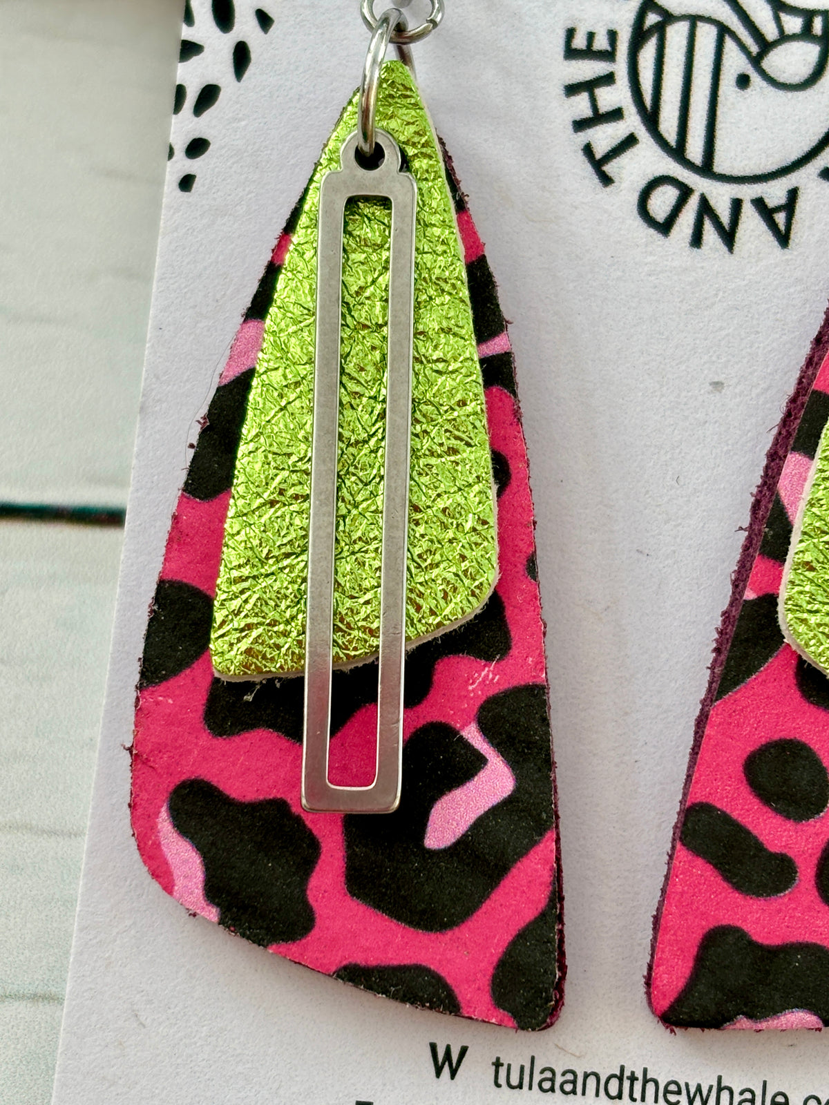 closeup shot of handmade earrings with pink leopard print, lime green leather, and silver accent—bold, nature-inspired design