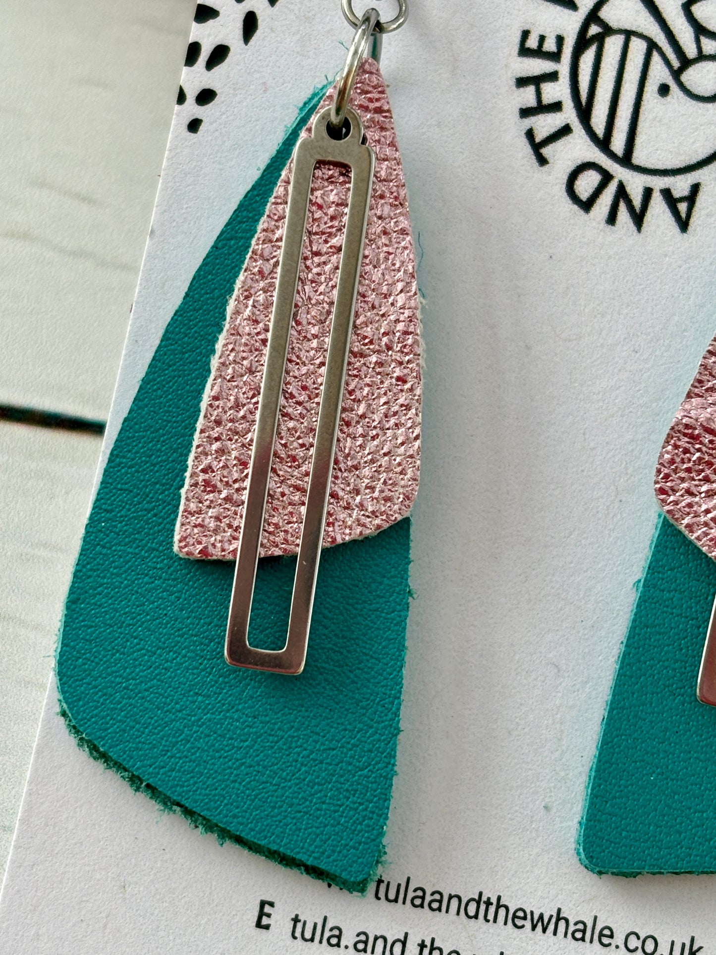 closeup shot of handmade teal and rose pink leather earrings with gold geometric accent—bold, lightweight statement jewelry