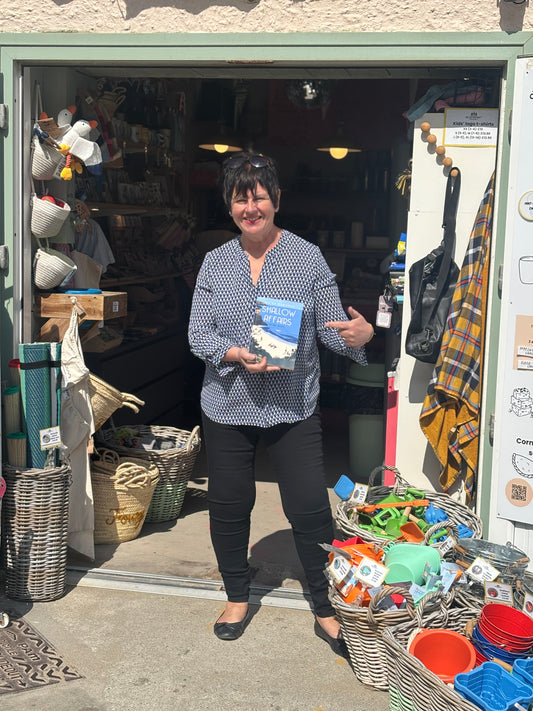 Woman standing in front of Readymoney Beach Shop holding a book.