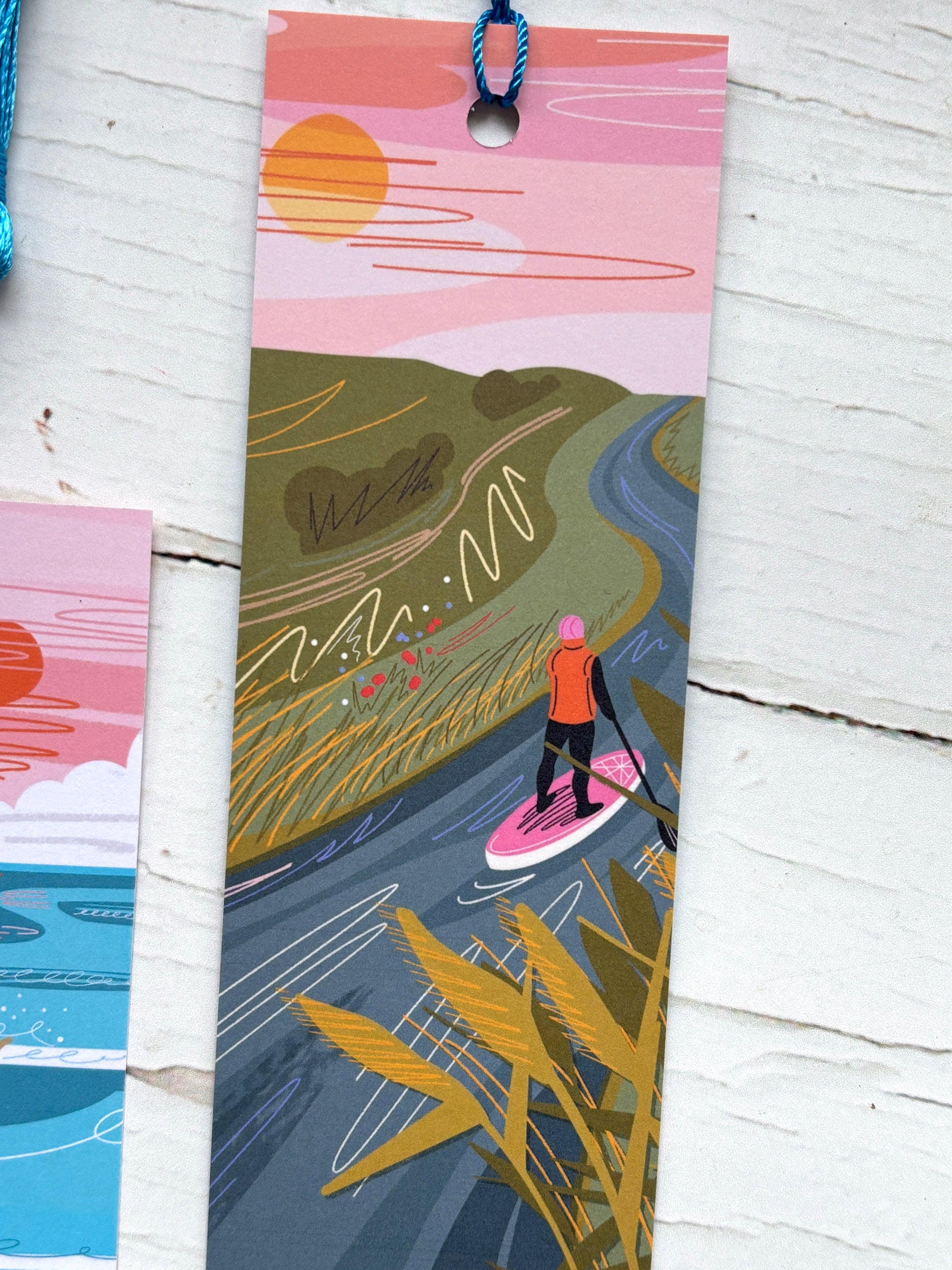 illustrated bookmark featuring paddleboarding on a winding river through coastal reeds pink and green art print