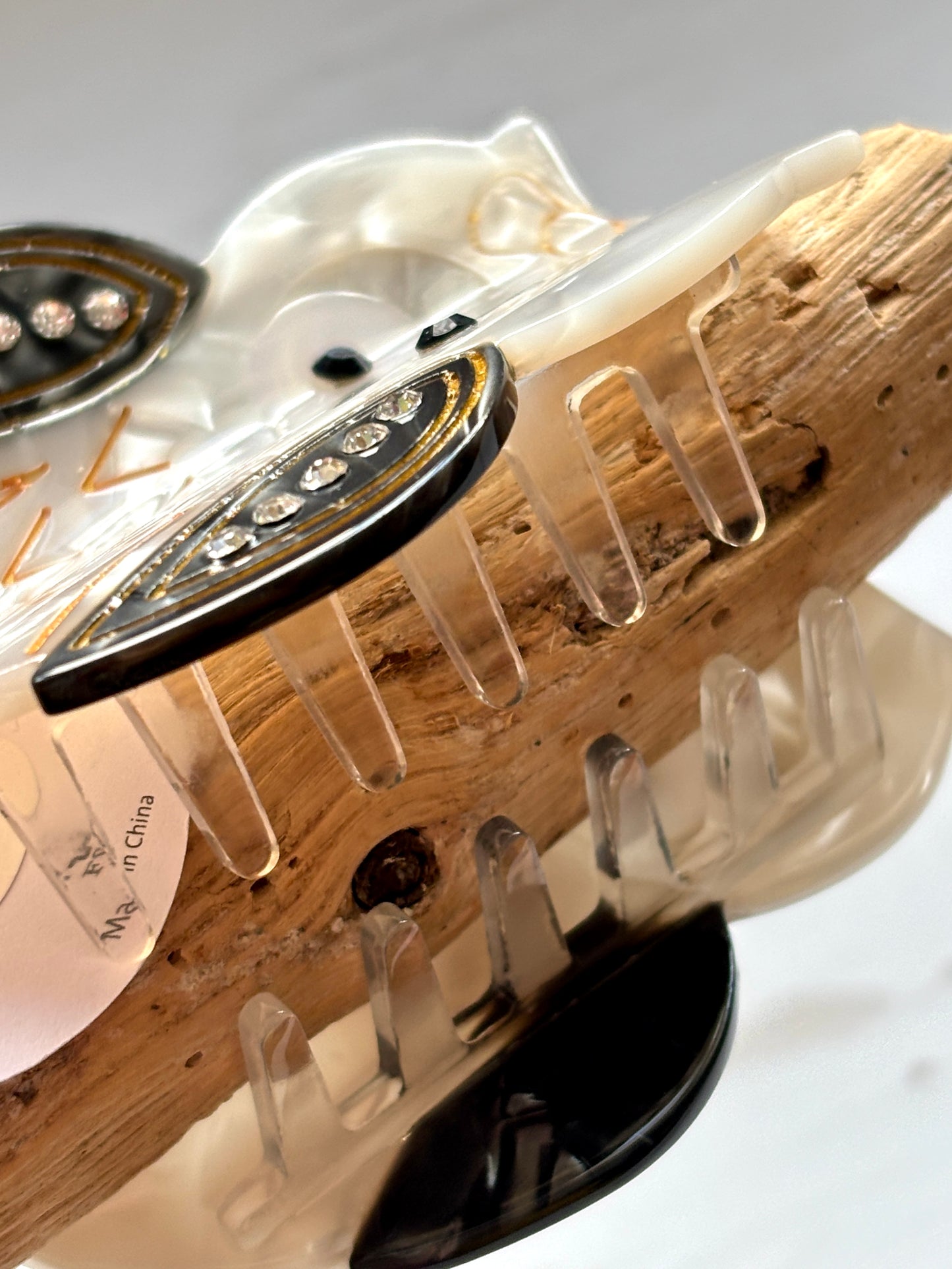 closeup shot of owl hair claw—translucent clip with rhinestones, gold feather details, secure grip, and whimsical woodland style