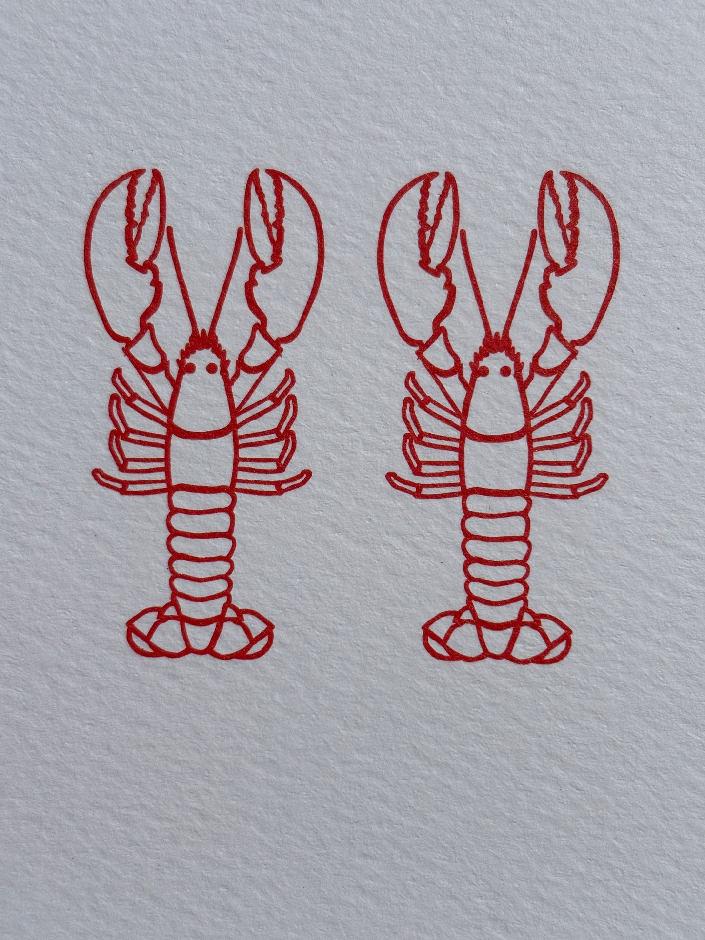 closeup shot of two identical red lobster line-drawings minimalist nautical art for a romantic, coastal or anniversary greeting card