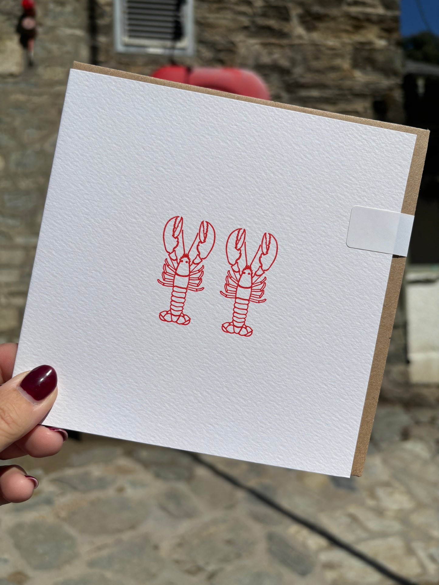 outdoor photo of a square white card featuring two red lobsters minimalist nautical stationery for unique or romantic gifts