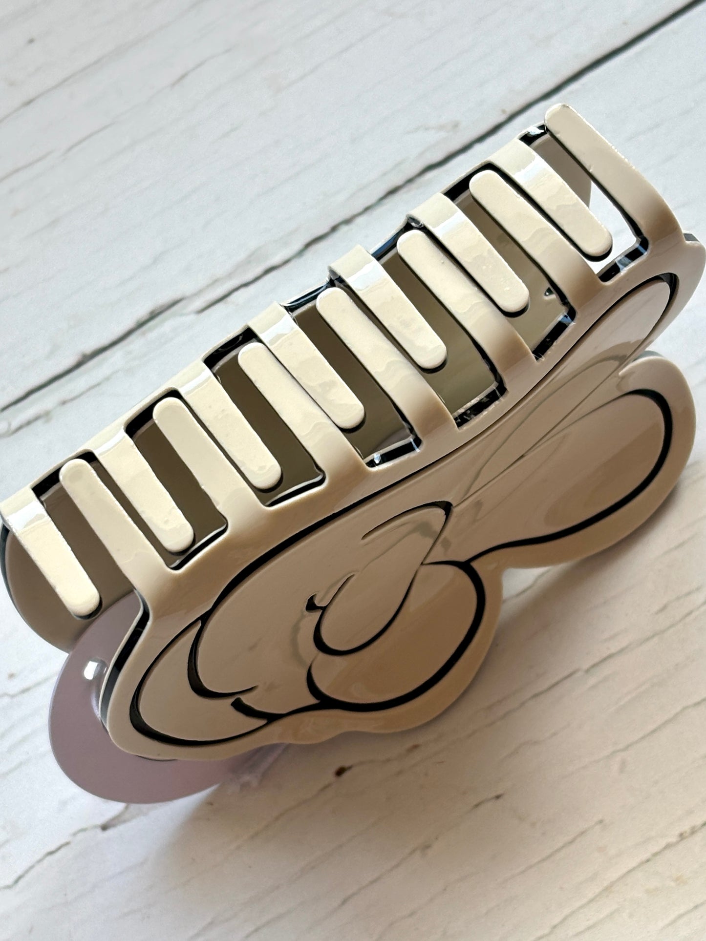 closeup shot of peace sign hair claw clip trendy large cartoon V-gesture accessory Y2K aesthetic, cream & black statement jaw clip