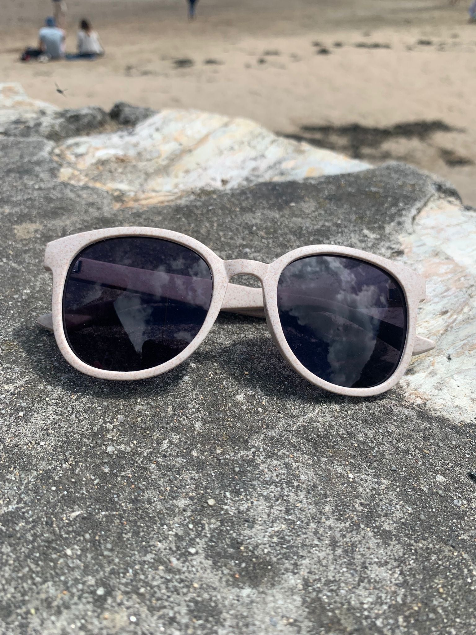 eco-friendly sunglasses for 'Readymoney Beach Shop.' beige/pink recycled plastic frame, black lenses, beach eyewear, sustainable style