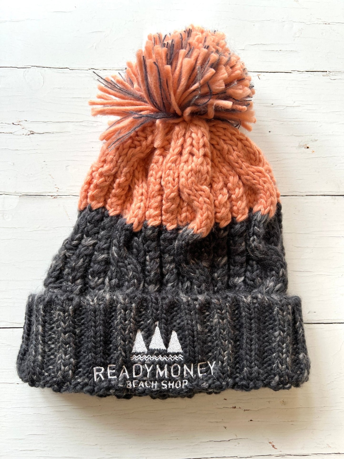 pink-grey chunky bobble hat with faux fur pom-pom and beach shop logo—soft, stylish, and perfect for cozy winter days