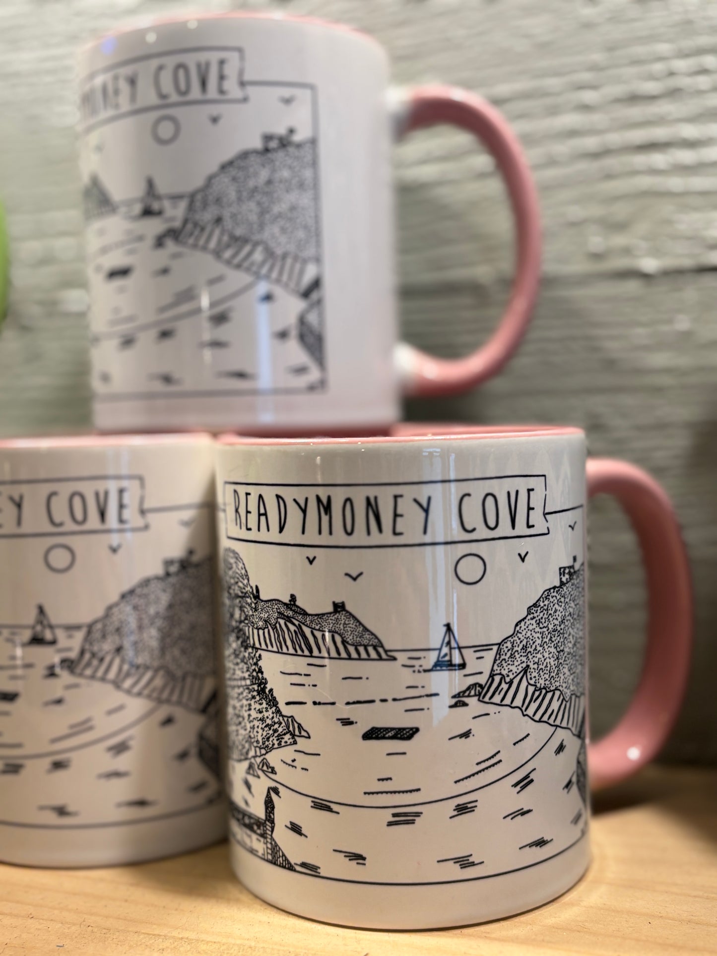 a mug with a black & white illustration of readymoney cove, pale pink handle and interior
