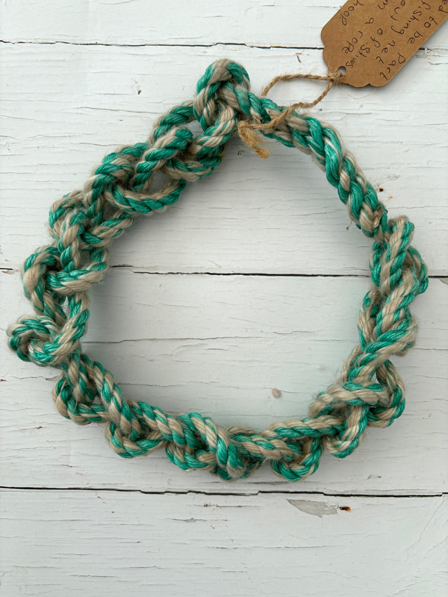 closeup shot of knotted dog toy hoop made from upcycled green/natural fishing rope durable, nautical, eco-friendly pet accessory, rope toy