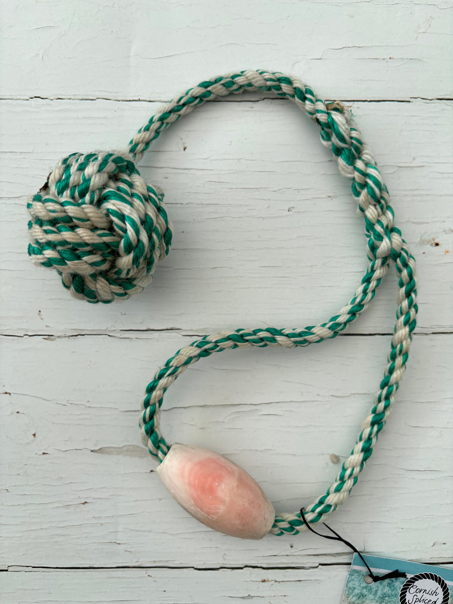 closeup shot of eco-friendly floating dog tug toy made from upcycled green/natural fishing rope with a buoyant pink float