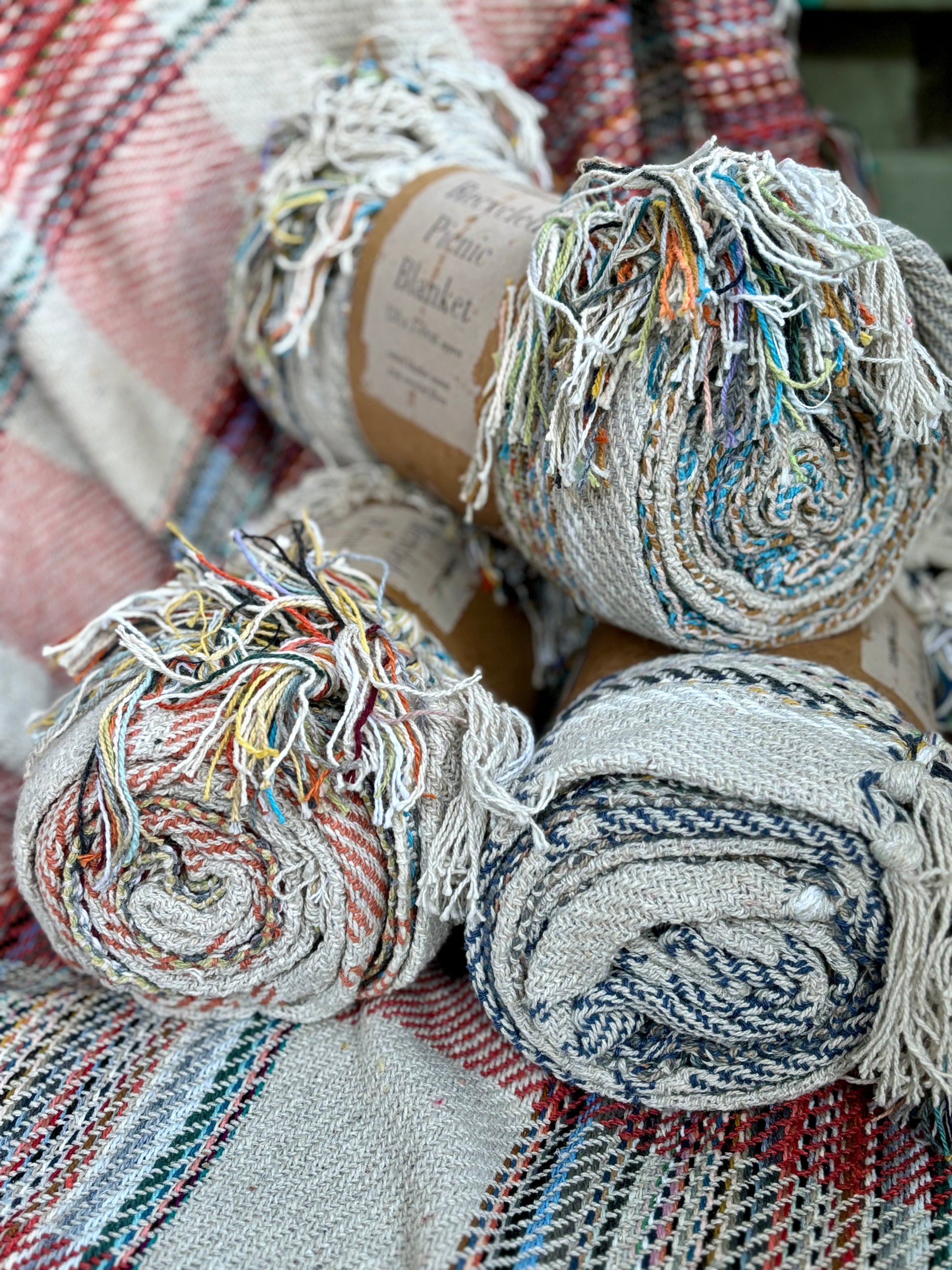 rolled up, multi-colored recycled cotton picnic blankets/throws sustainable, fringed home decor, eco-friendly, woven recycled fibre