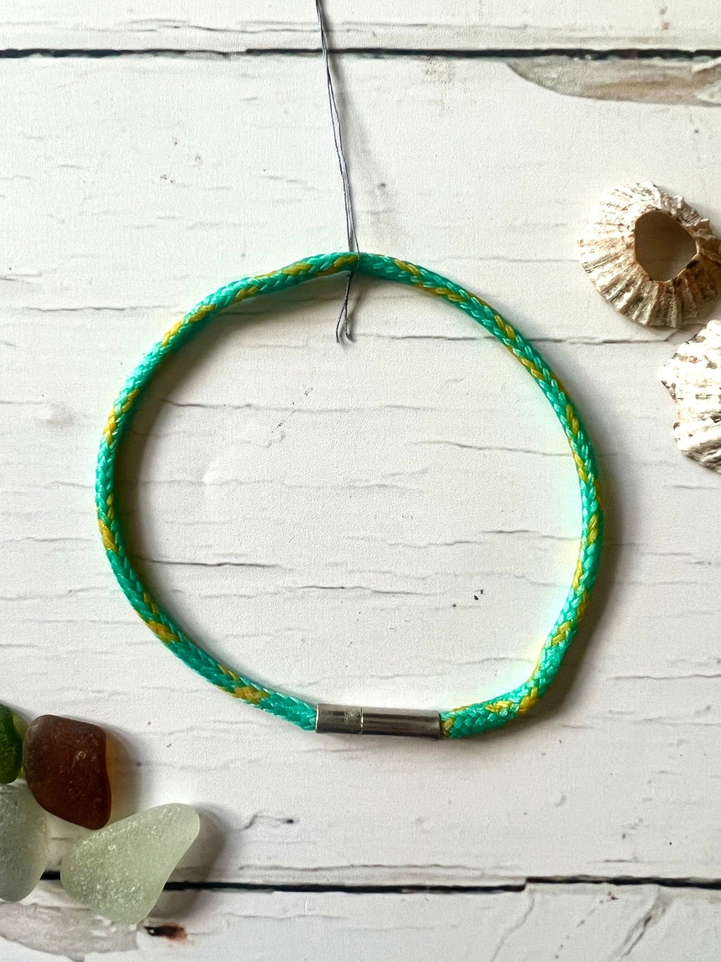 sustainable bracelet made from light blue yellow recycled ghost fishing net braided cord, nautical look, eco-friendly clasp