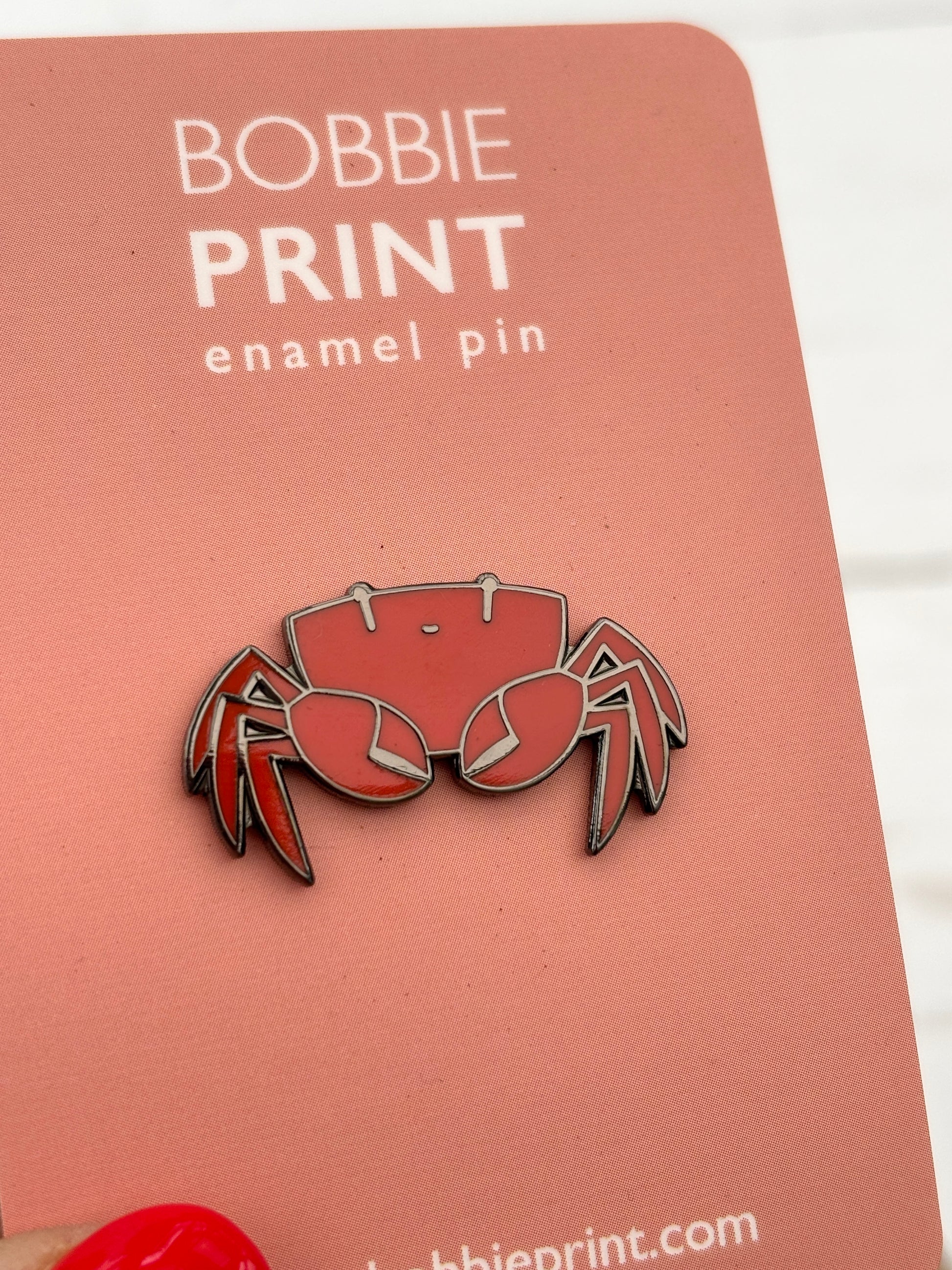 closeup shot of red crab enamel pin badge Bobbie Print metal backing detailed crustacean design lapel pin ocean theme accessory