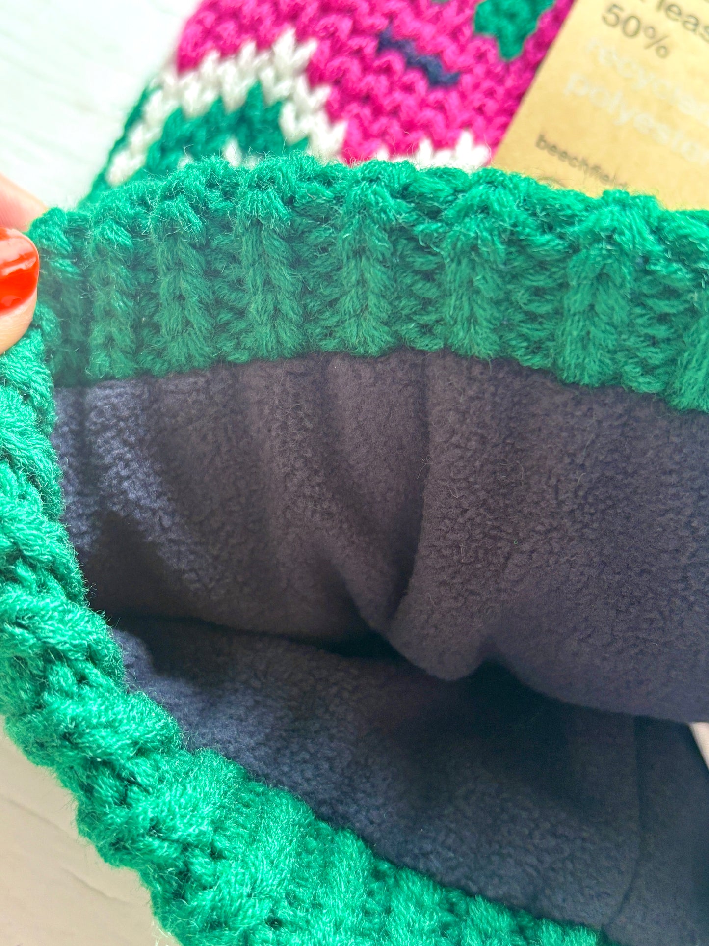 retro knit bobble hat with fleece lining, green ribbed brim, and pink-white zigzag pattern—warm, vibrant winter accessory