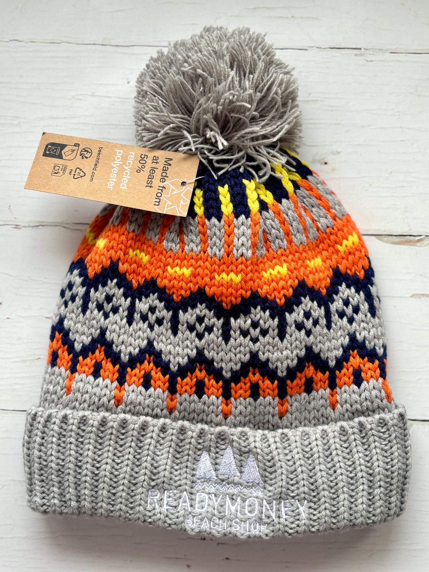 retro knit bobble hat with gray ribbed brim, bold orange-yellow zigzag pattern, and beach shop logo—stylish warmth for winter days
