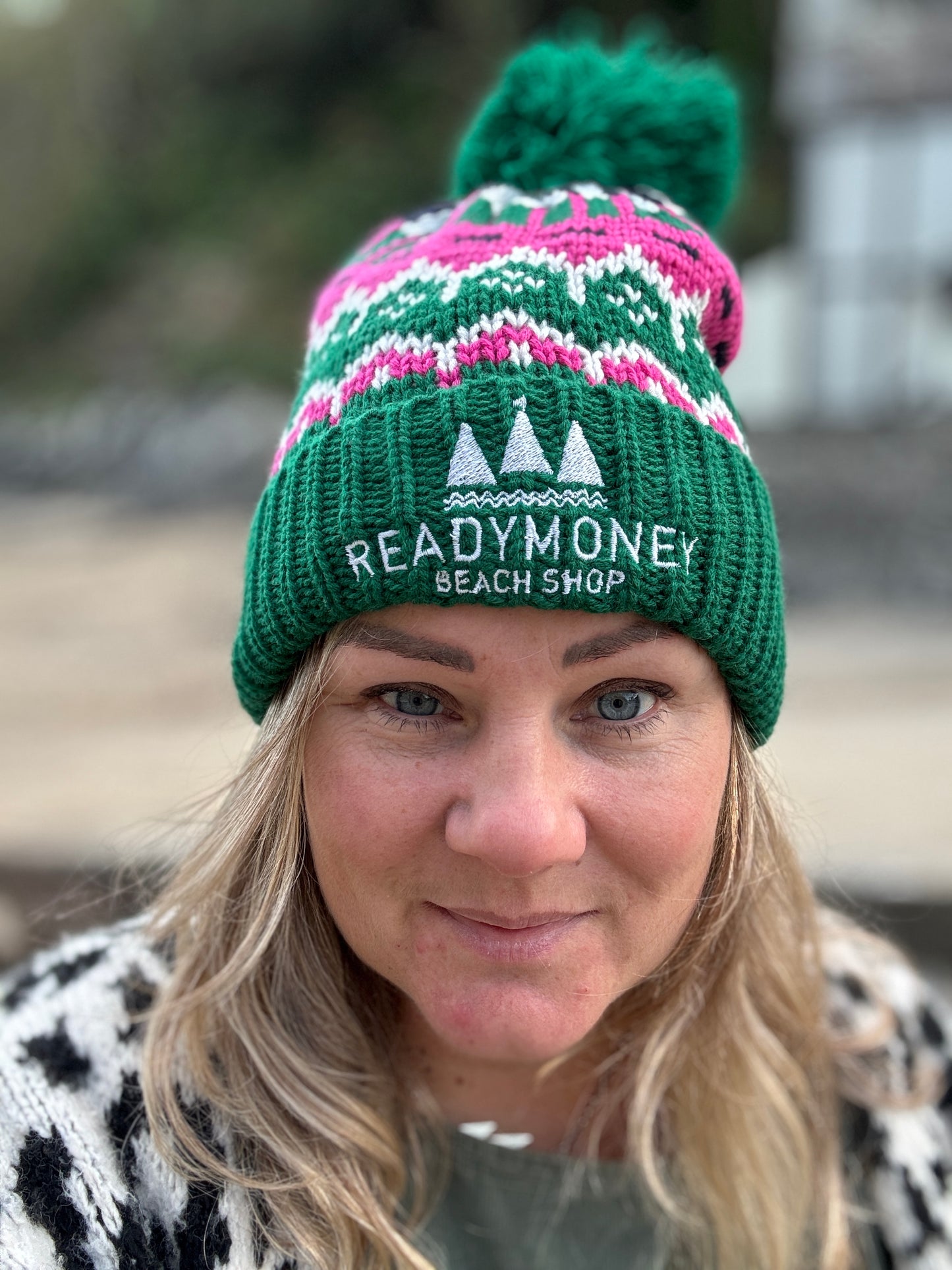 retro bobble hat with green ribbed brim, playful pink-white knit, and embroidered beach shop logo—fun, cozy gear for winter outings
