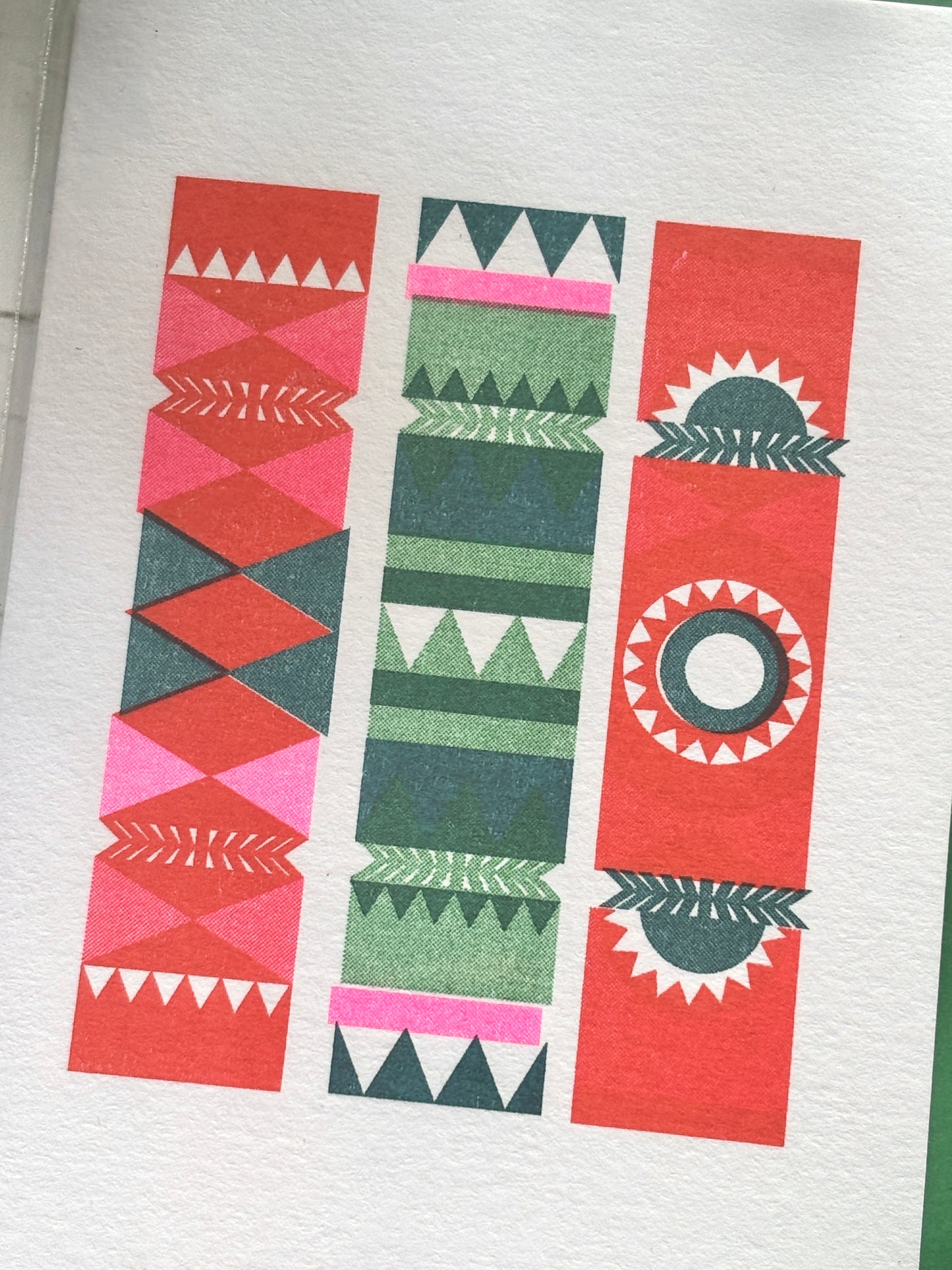 closeup shot of retro style Christmas card with three colorful crackers in red, green, and pink, festive geometric holiday design