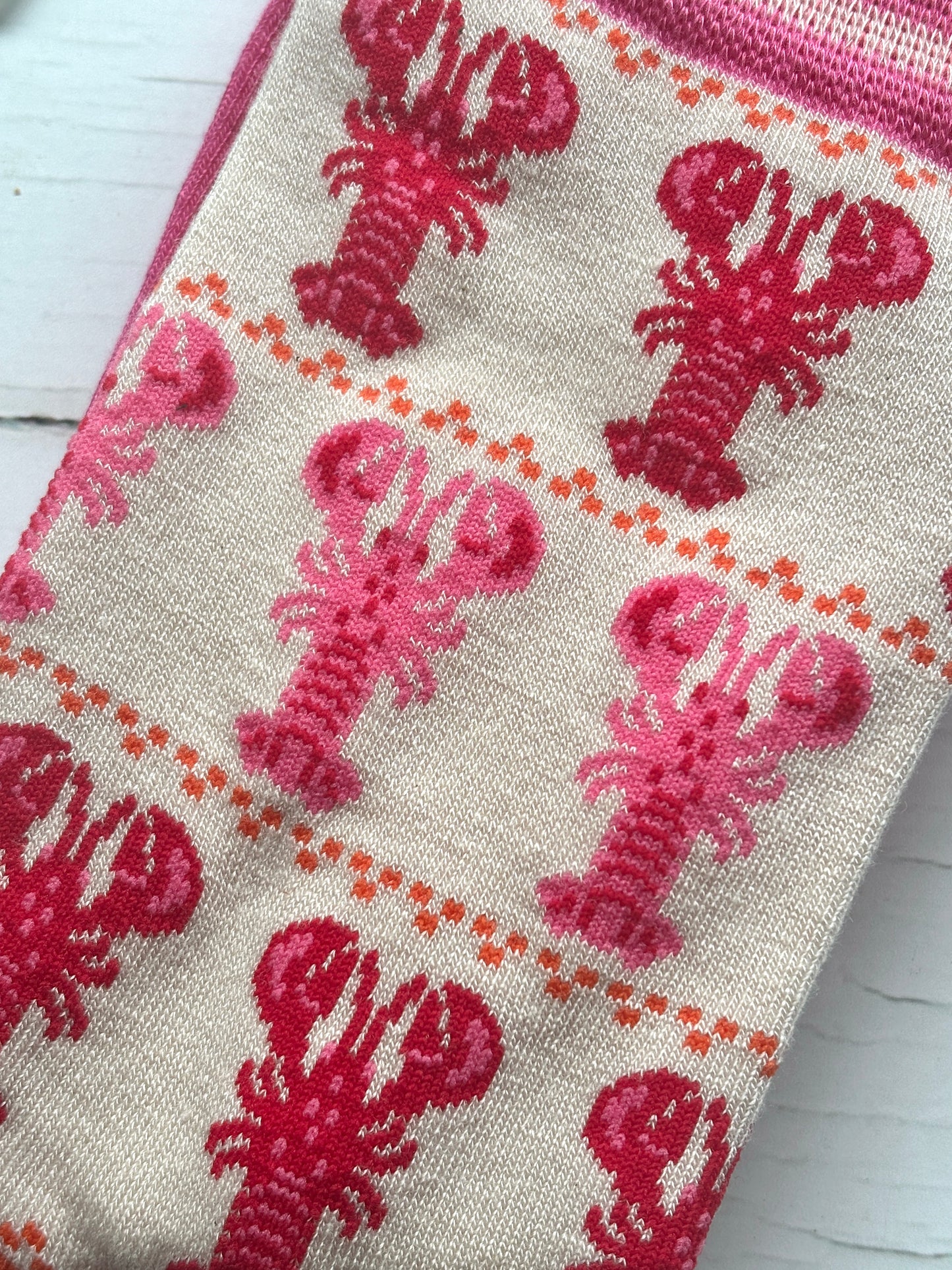closeup shot of knit pattern of bamboo socks with rows of pink and red lobsters bright orange accents create unique coastal apparel