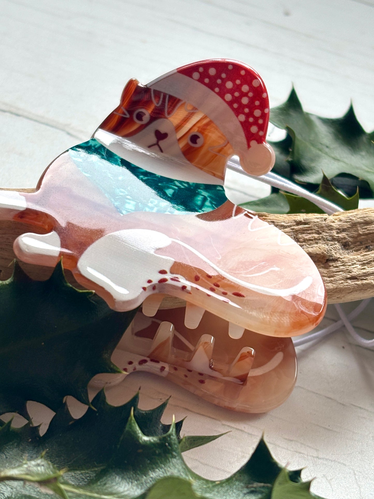closeup shot of a holiday cat hair clip orange tortoiseshell acrylic cat wearing a Santa hat and sparkly teal scarf festive feline accessory