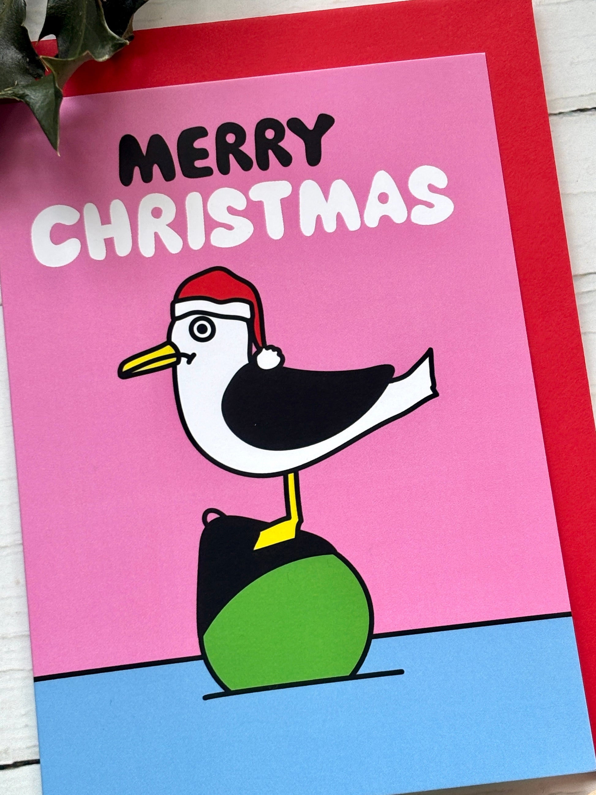 Cute seagull Christmas card with Santa hat and “Merry Christmas” text on pink background, fun festive holiday greeting design