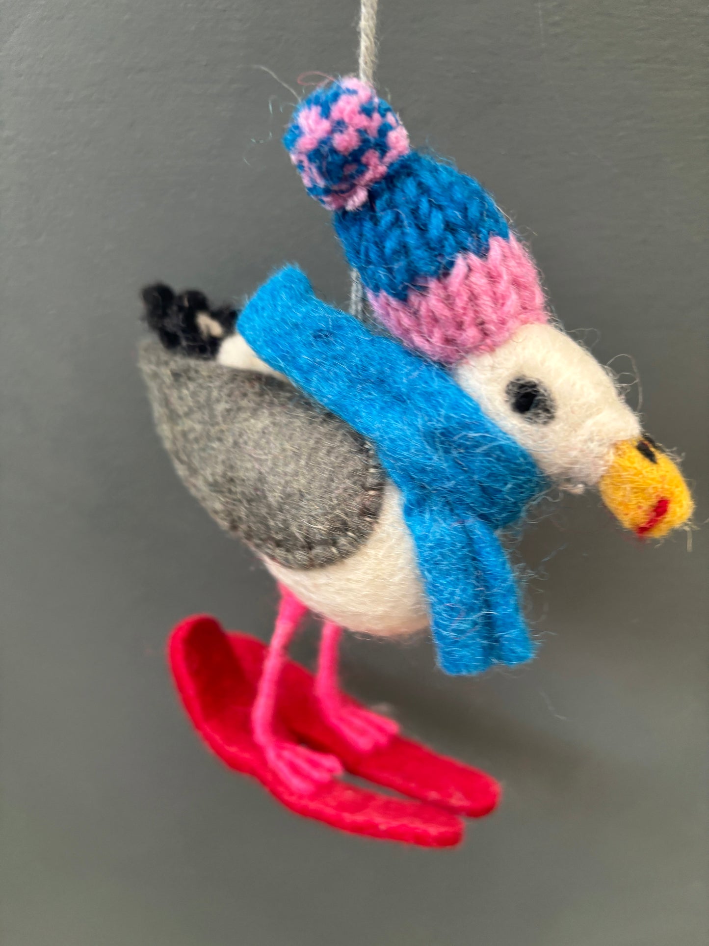 closeup shot of felt seagull Christmas ornament with skis, knit hat, and scarf—playful coastal winter holiday decor