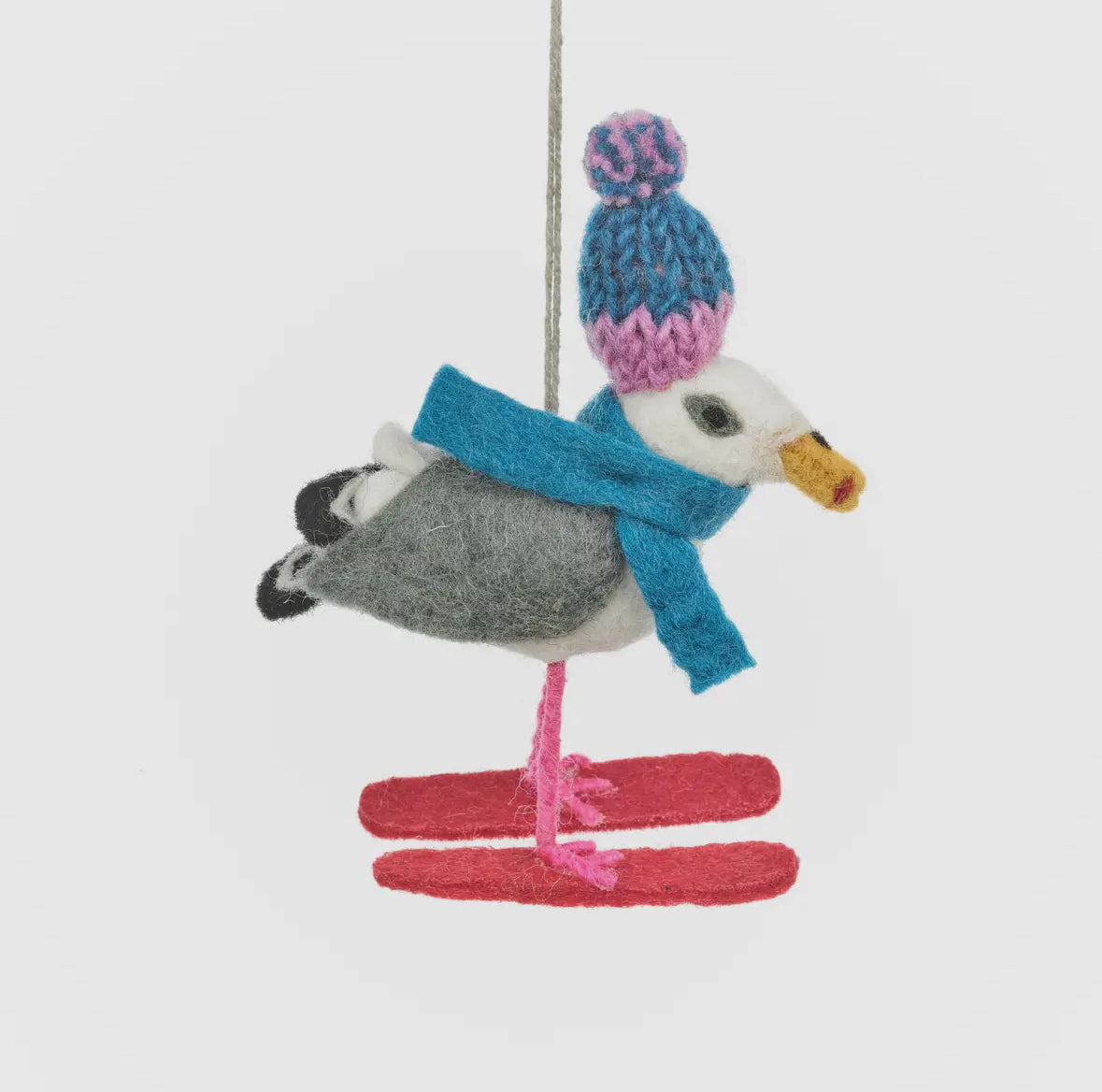 closeup shot of felt seagull ornament with red skis, knit hat, and scarf—coastal Christmas tree decor with winter whimsy