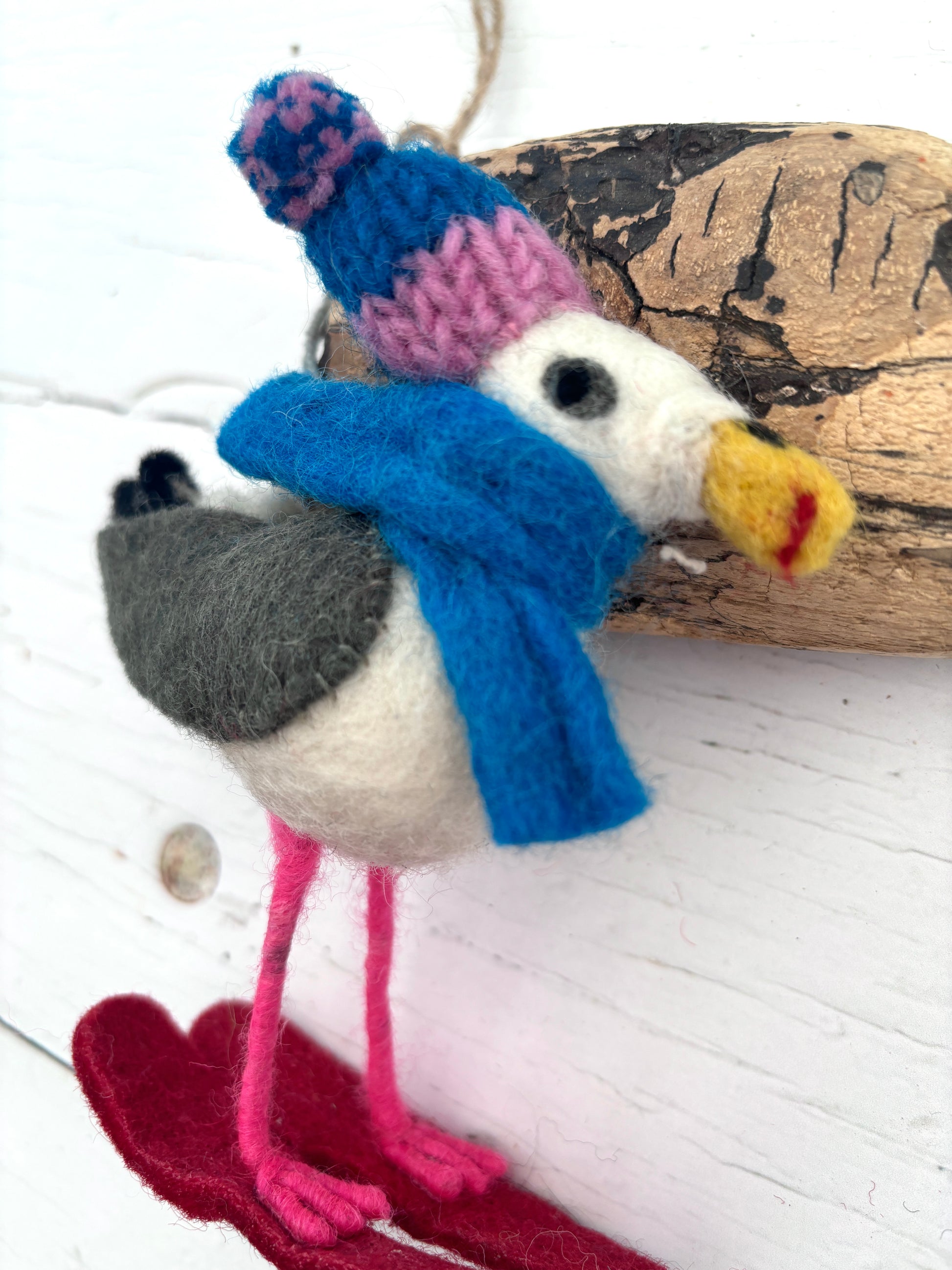 side view of felt seagull ornament with skis, knit hat, and scarf—coastal Christmas decor with winter charm
