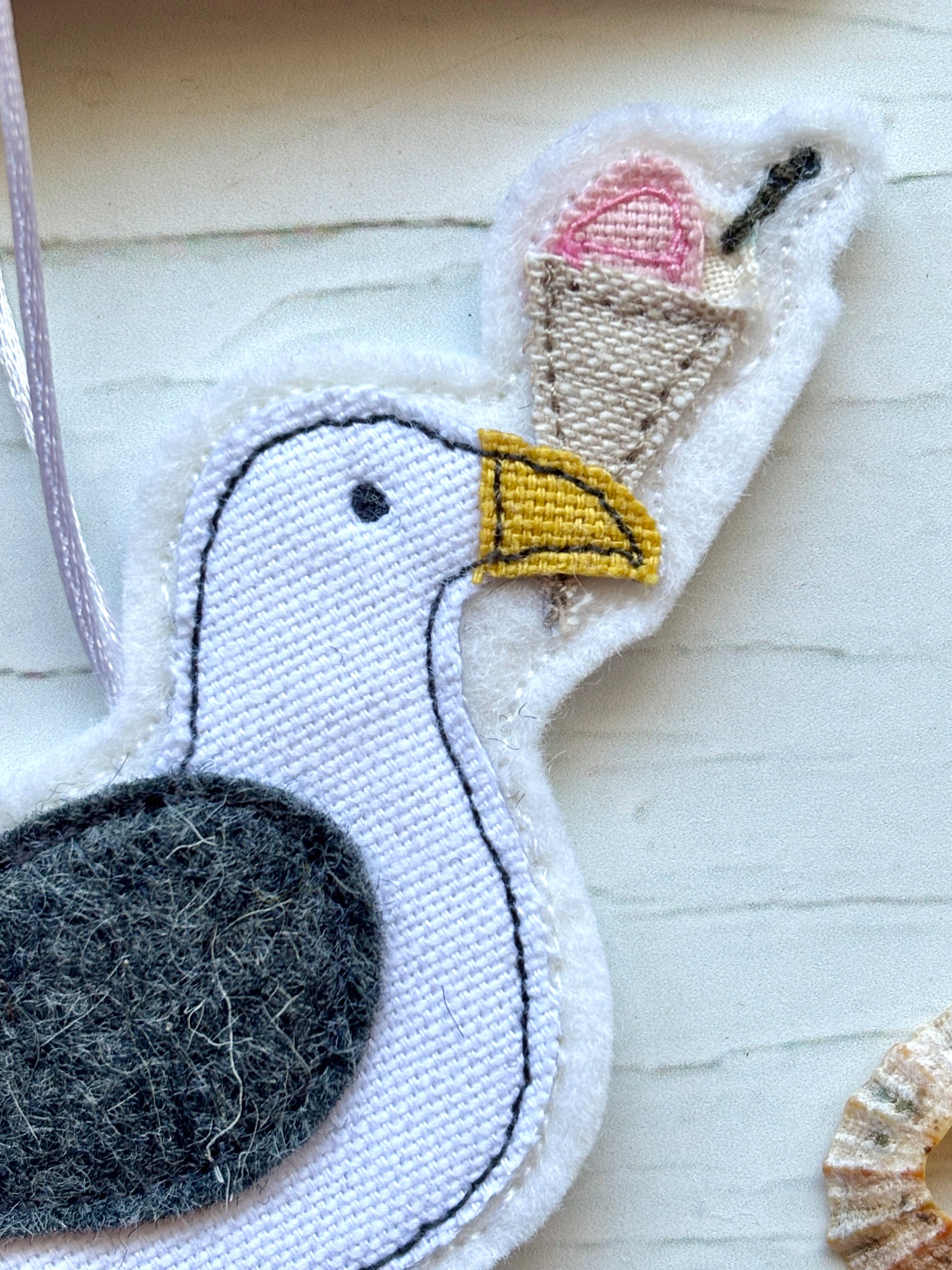 closeup shot of handmade felt seagull with ice cream cone—quirky coastal hanging decor for summer or seaside styling