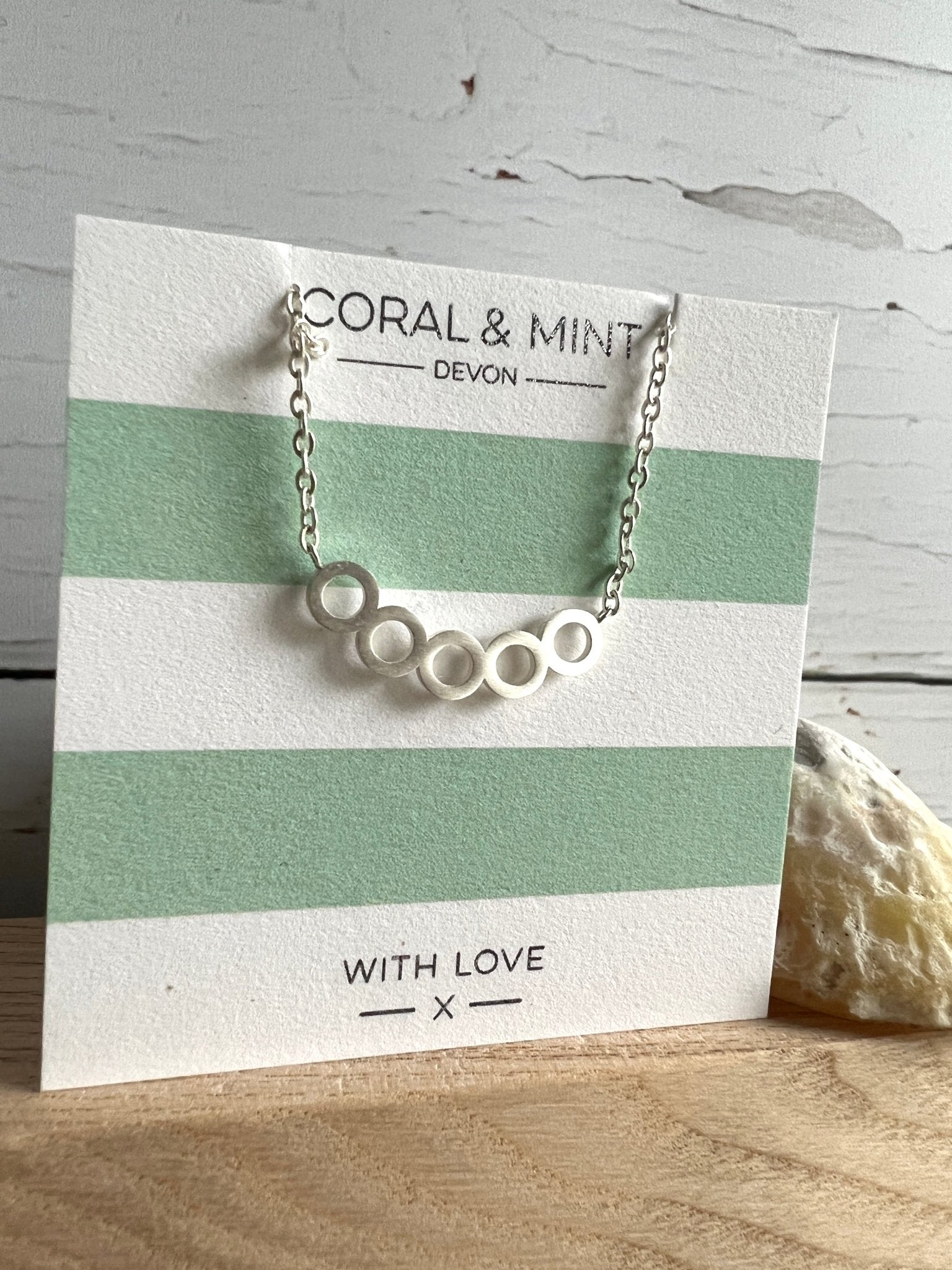 silver bubble circle pendant necklace by Coral & Mint minimalist geometric jewelry on striped gift card chic gift