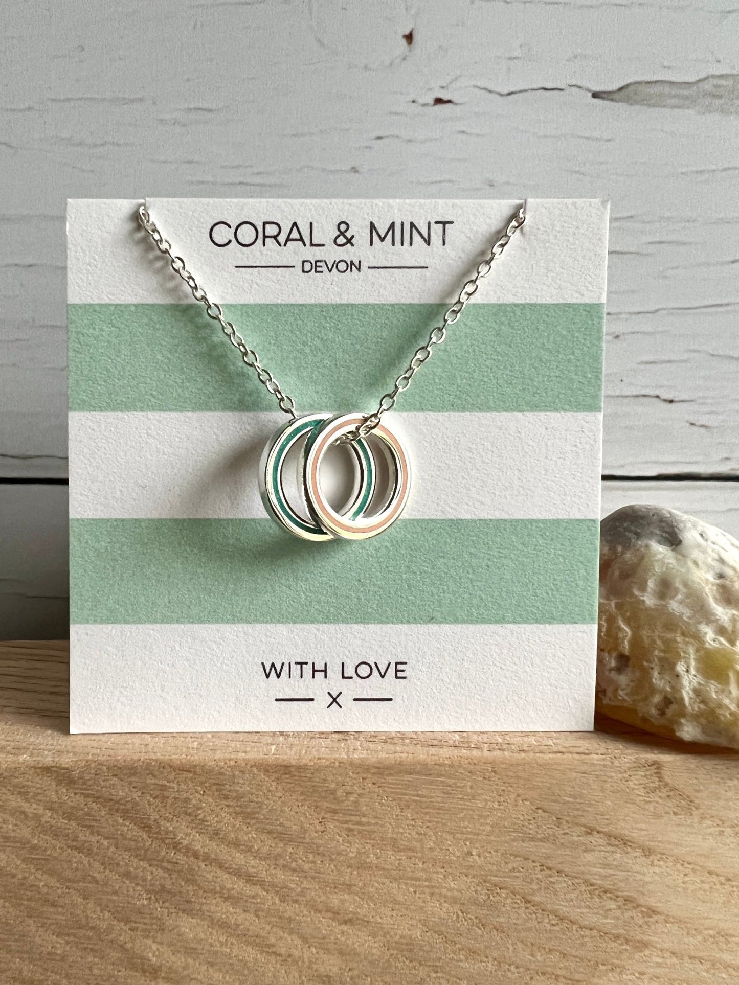 silver necklace with interlocking mint and white enamel rings dainty geometric jewelry on a striped gift card
