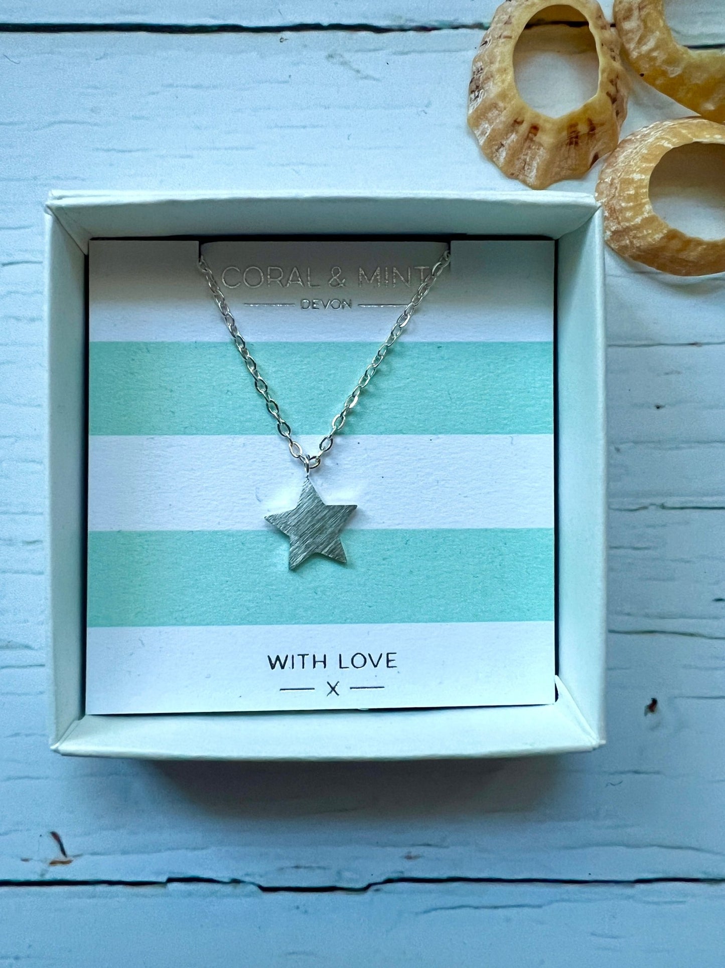 silver brushed star pendant necklace by Coral & Mint dainty celestial jewelry on a striped gift card chic gift idea