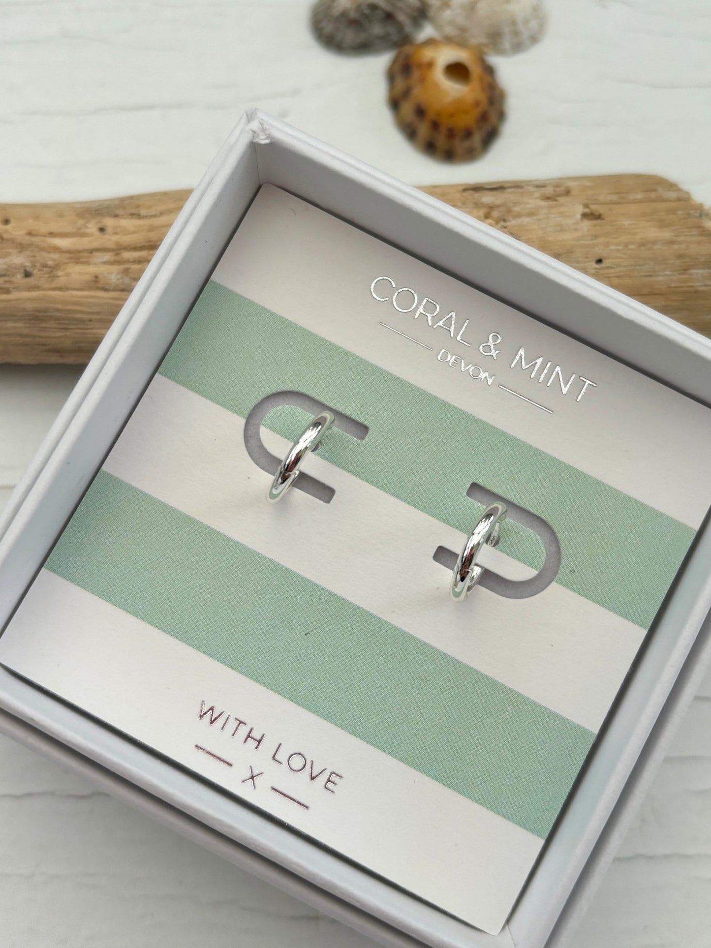 silver huggie hoop earrings by Coral & Mint minimalist silver jewelry on a striped gift card classic everyday gift idea