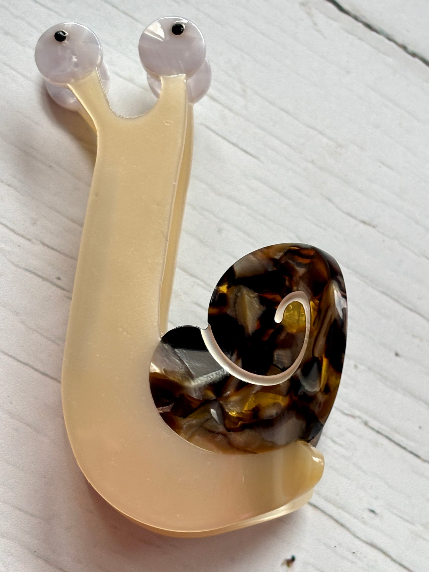 closeup shot of snail hair claw—marbled shell, translucent body, and quirky eyes for playful, nature-inspired hair styling