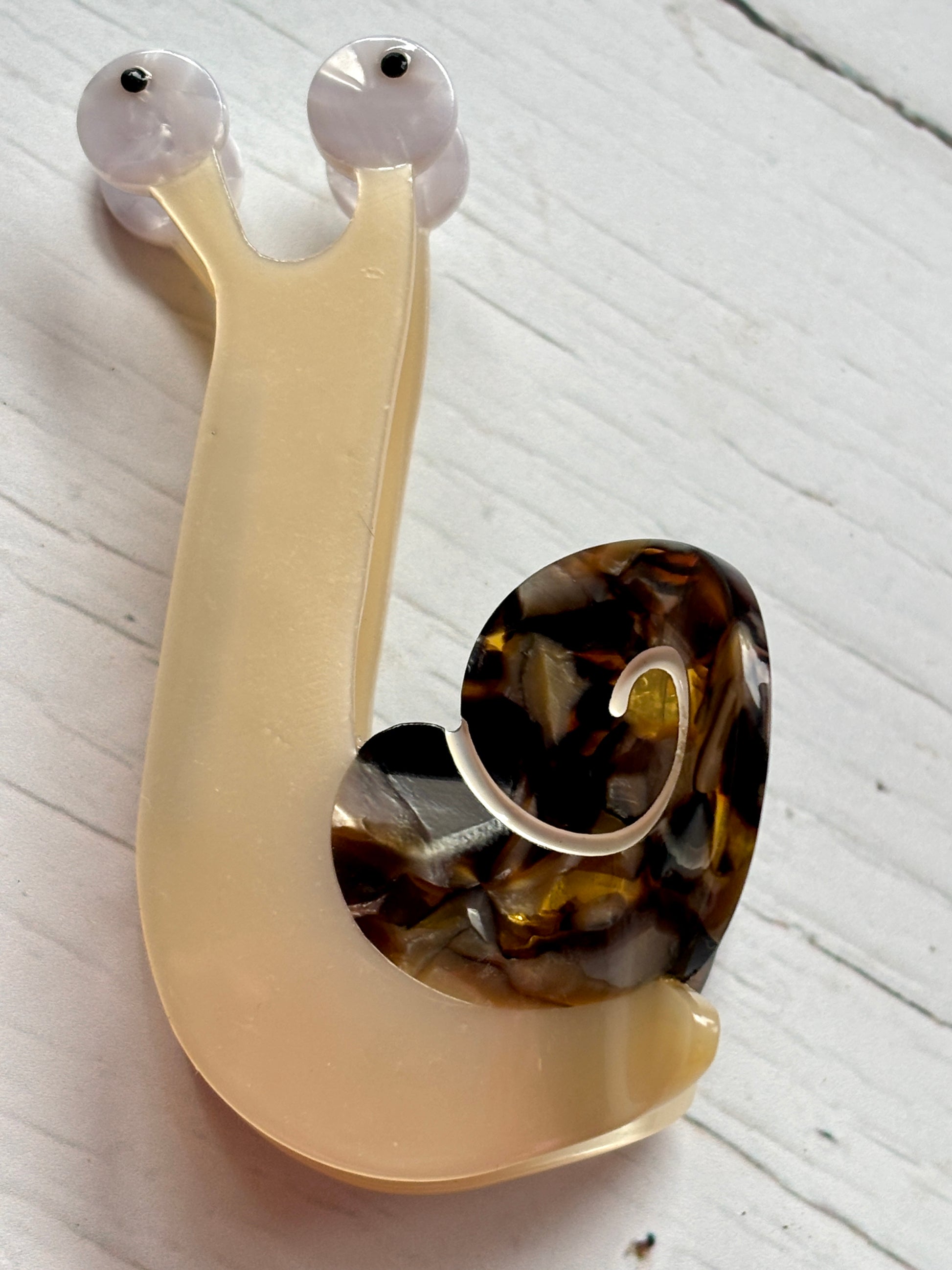 closeup shot of snail hair claw—marbled shell, translucent body, and quirky eyes for playful, nature-inspired hair styling