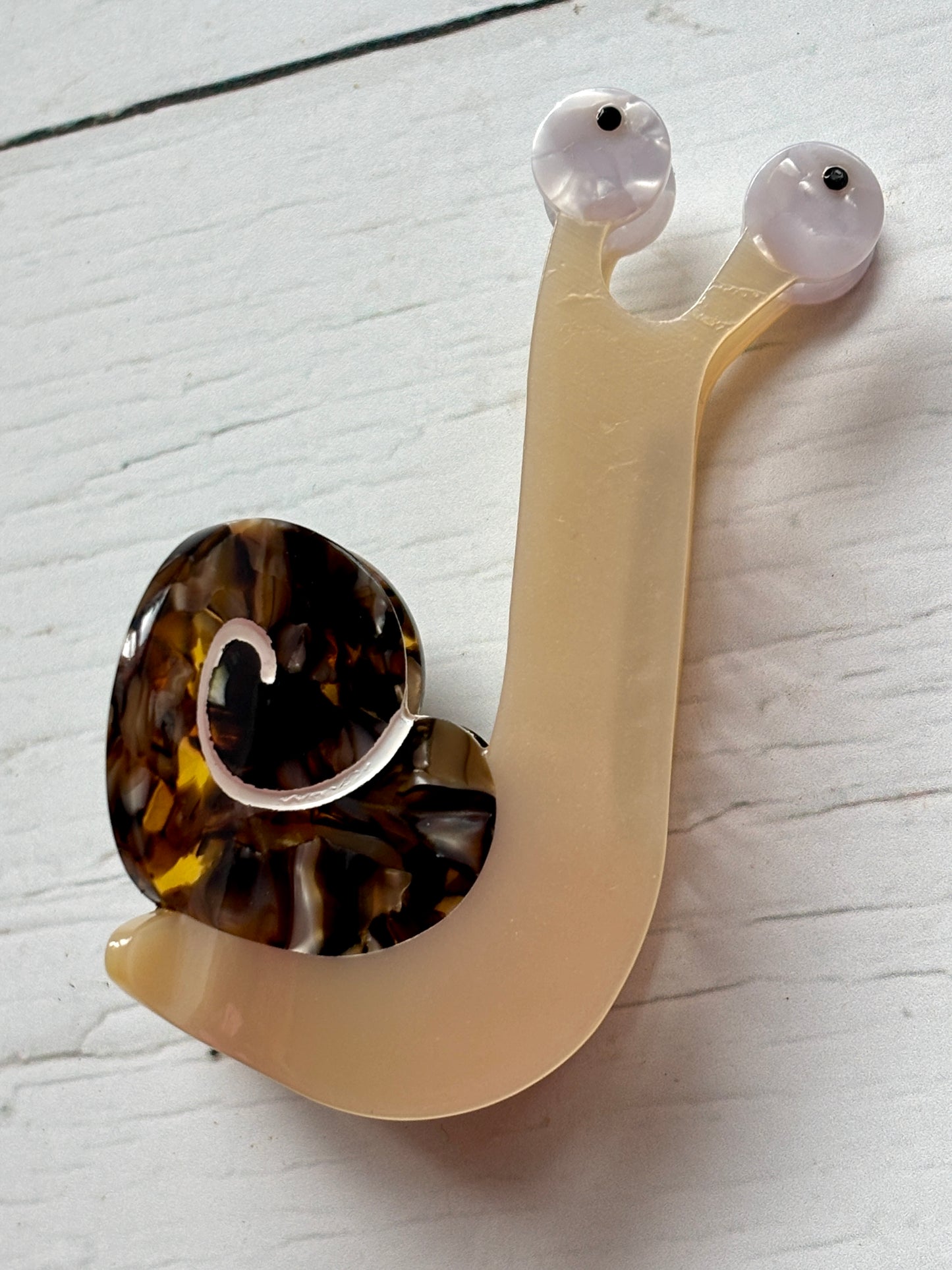 snail hair claw—glossy marbled shell, translucent body, and whimsical eyes for quirky, nature-inspired styling