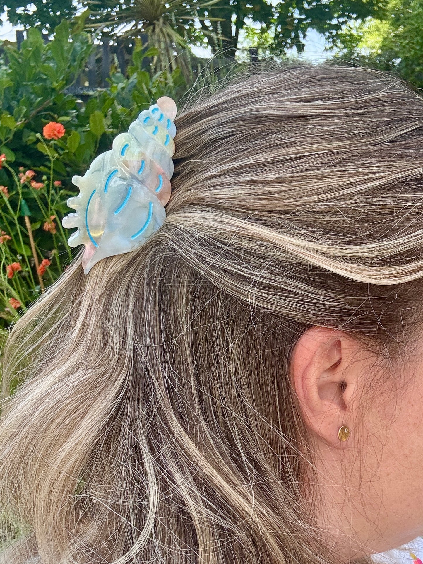 pastel spiral shell hair claw in beachy updo—iridescent clip adds coastal charm to summer hairstyles