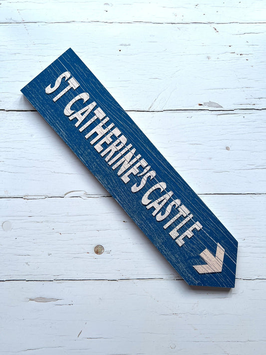 rustic blue wooden sign with white arrow—St Catherine’s Castle directional decor for coastal or heritage-themed styling