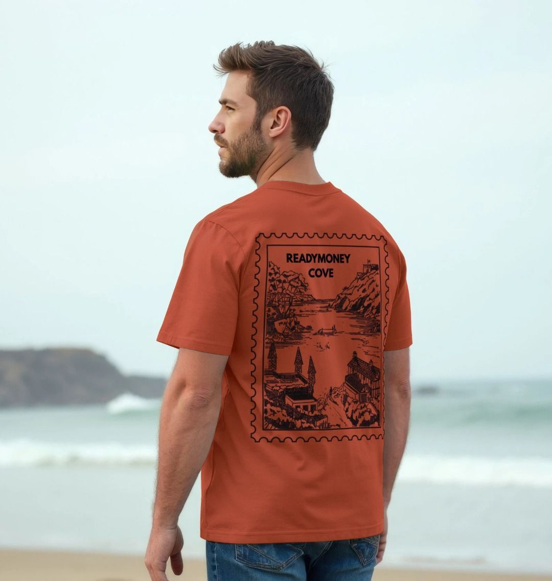 rust men’s tee with Readymoney Cove stamp back print—heritage coastal artwork styled for travel, beachwear, and outdoor escapes