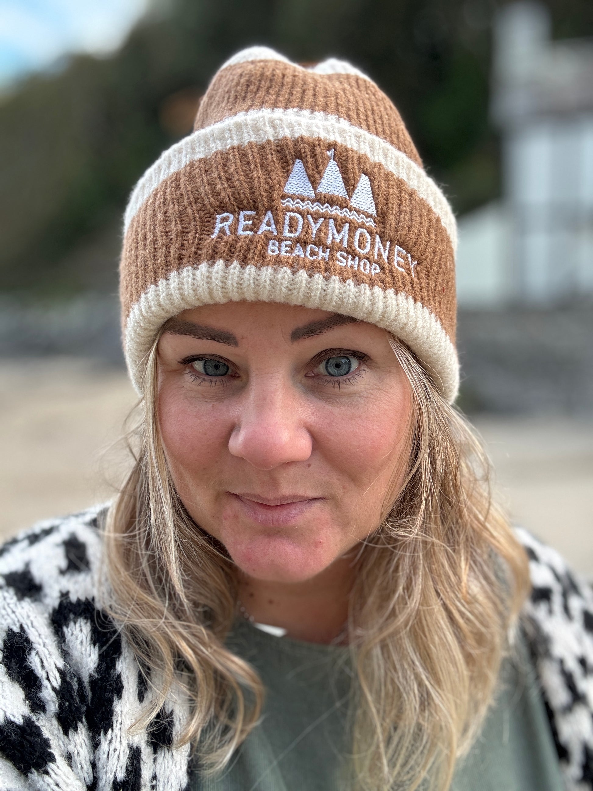 Readymoney Beach Shop beanie in cream and brown—cozy ribbed knit hat with coastal logo, styled for outdoor winter adventures